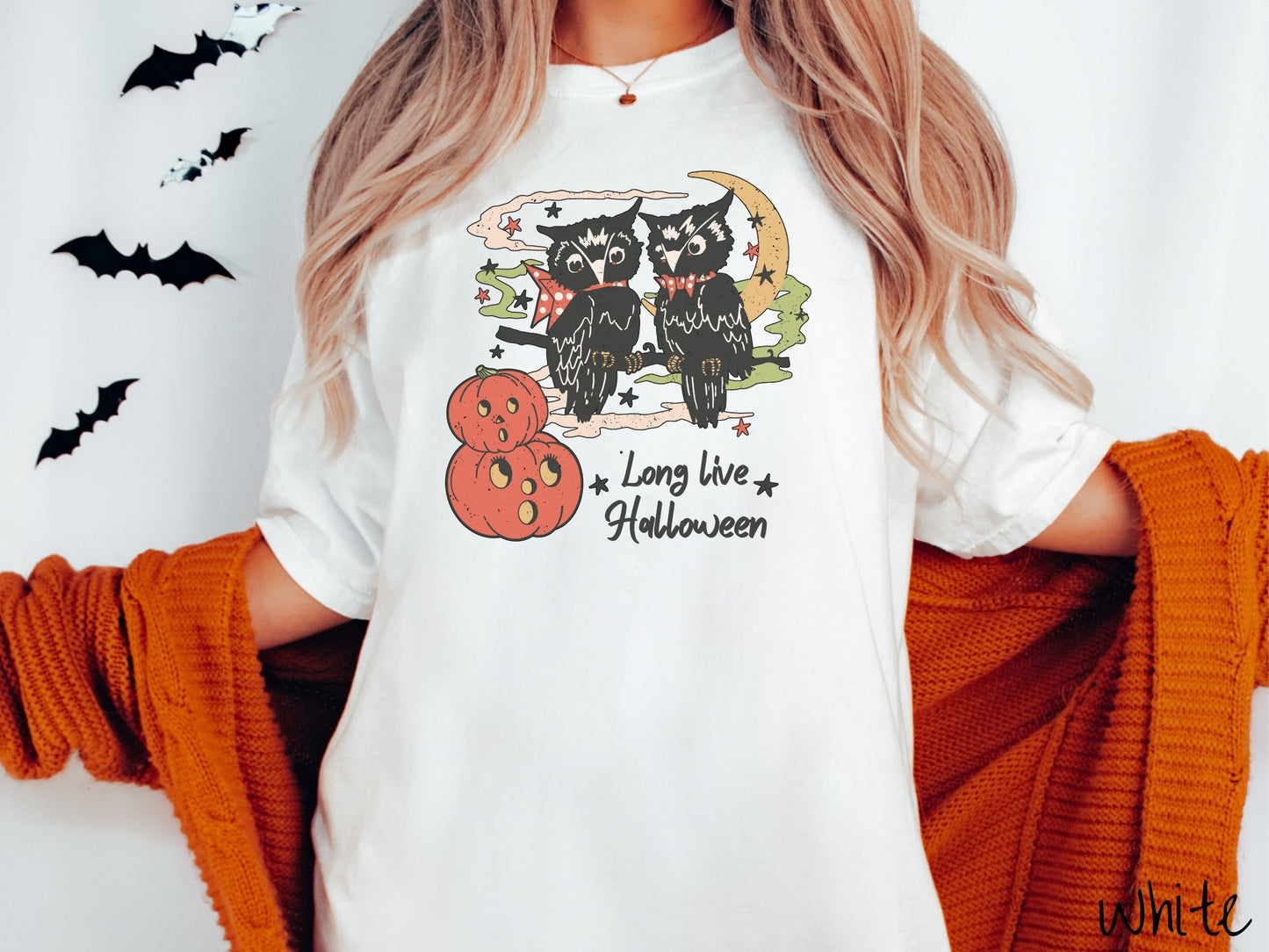 A woman wearing a cute, vintage white colored Comfort Colors T-shirt with the text Long Live Halloween in black font. Above are two black owls sitting on a tree branch by two scared pumpkins and surrounded by stars and the moon.