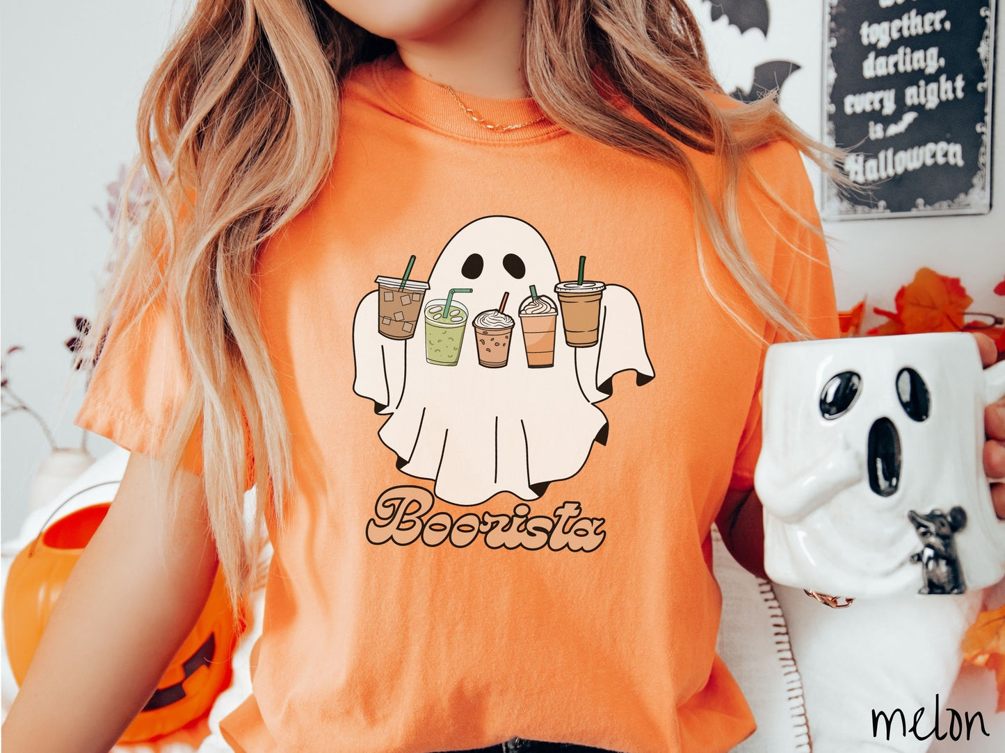 A woman wearing a cute, vintage melon colored Comfort Colors T-shirt with the text Boorista along the bottom. Above is a white ghost holding an iced coffee, a green matcha tea, a frappuccino, a pumpkin spiced latte, and an iced mocha latte.