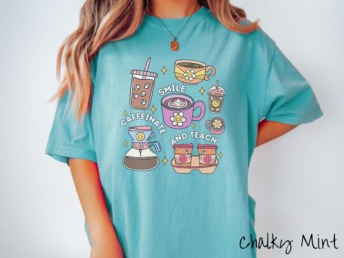 A woman wearing a cute, vintage chalky mint colored Comfort Colors T-shirt with text Smile Caffeinate and Teach. There is an iced coffee, two cups of hot coffee, a blended coffee drink with whipped cream, to-go coffees, and a pot of coffee.