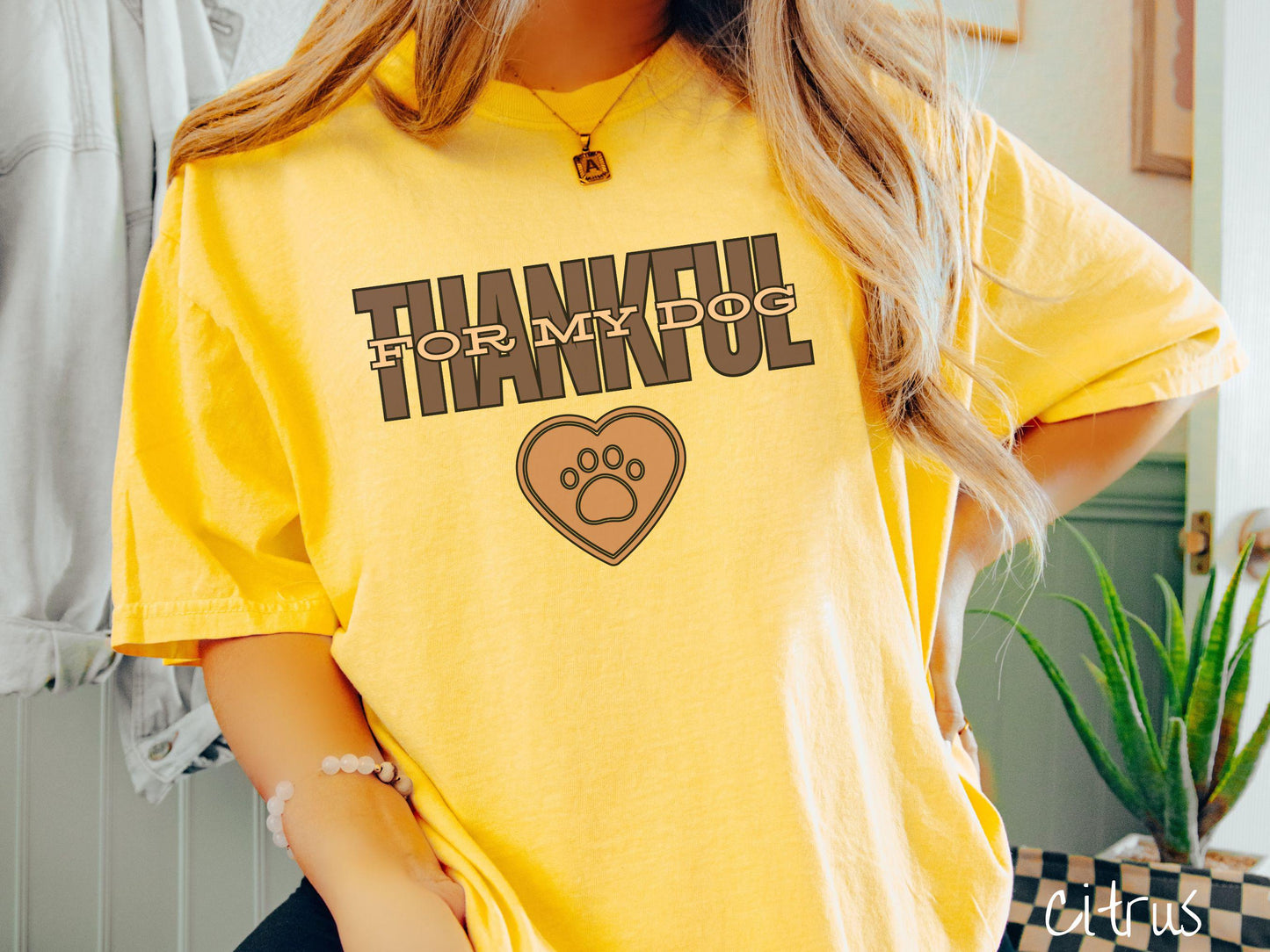 A woman wearing a cute, vintage citrus colored Comfort Colors T-shirt with the text Thankful for My Dog across the top in two shades of brown. Below is a brown heart with a dog paw print in the middle.