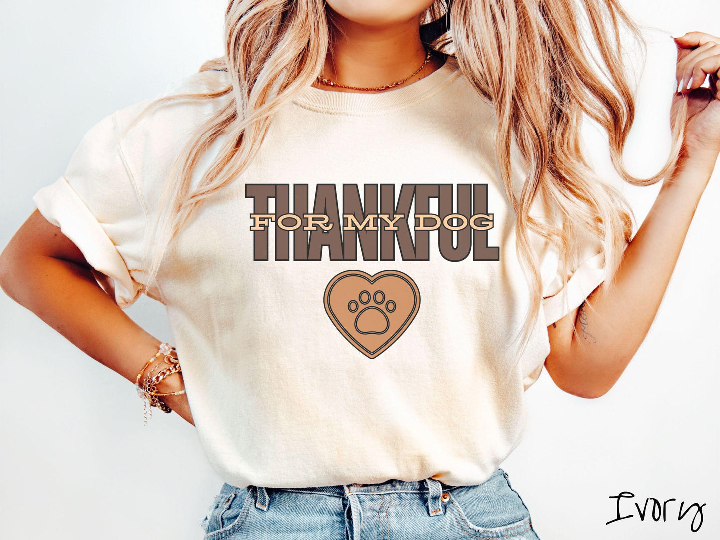 A woman wearing a cute, vintage ivory colored Comfort Colors T-shirt with the text Thankful for My Dog across the top in two shades of brown. Below is a brown heart with a dog paw print in the middle.