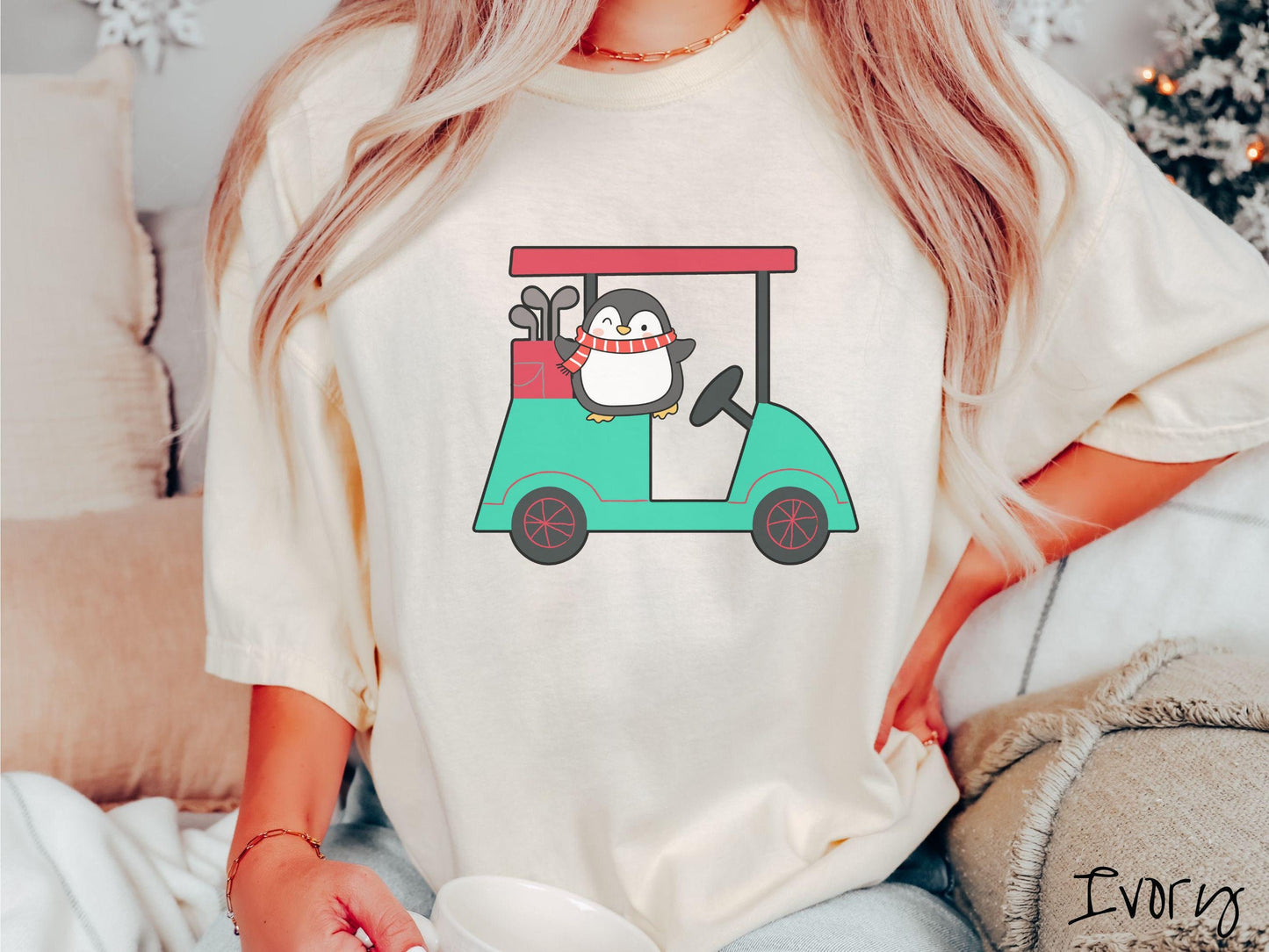 A woman wearing a cute ivory colored shirt with smiling penguin driving a green golf cart and waving with both hands.