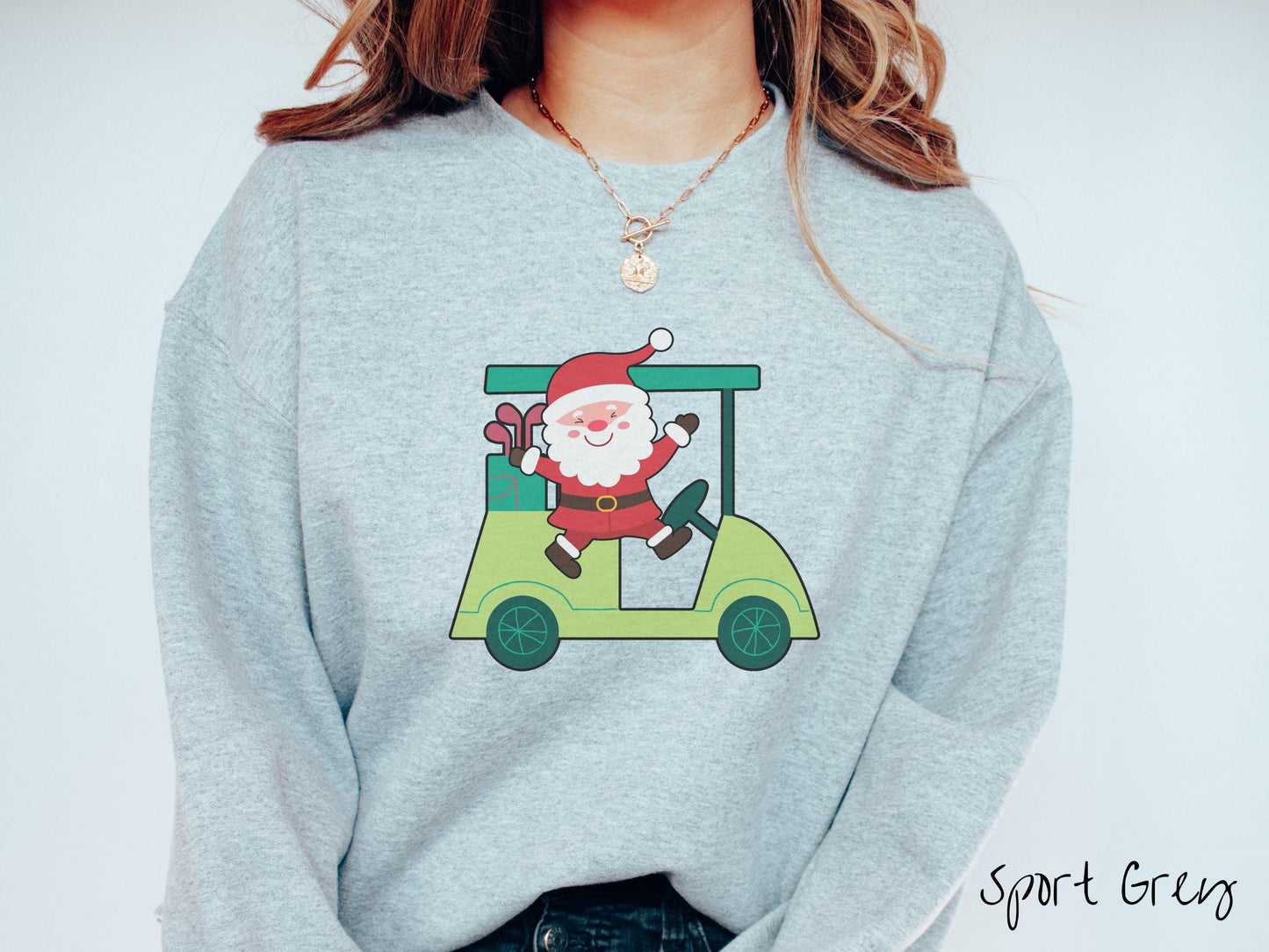 A woman wearing a cute sport grey colored sweatshirt with smiling Santa driving a green golf cart and waving with both hands.