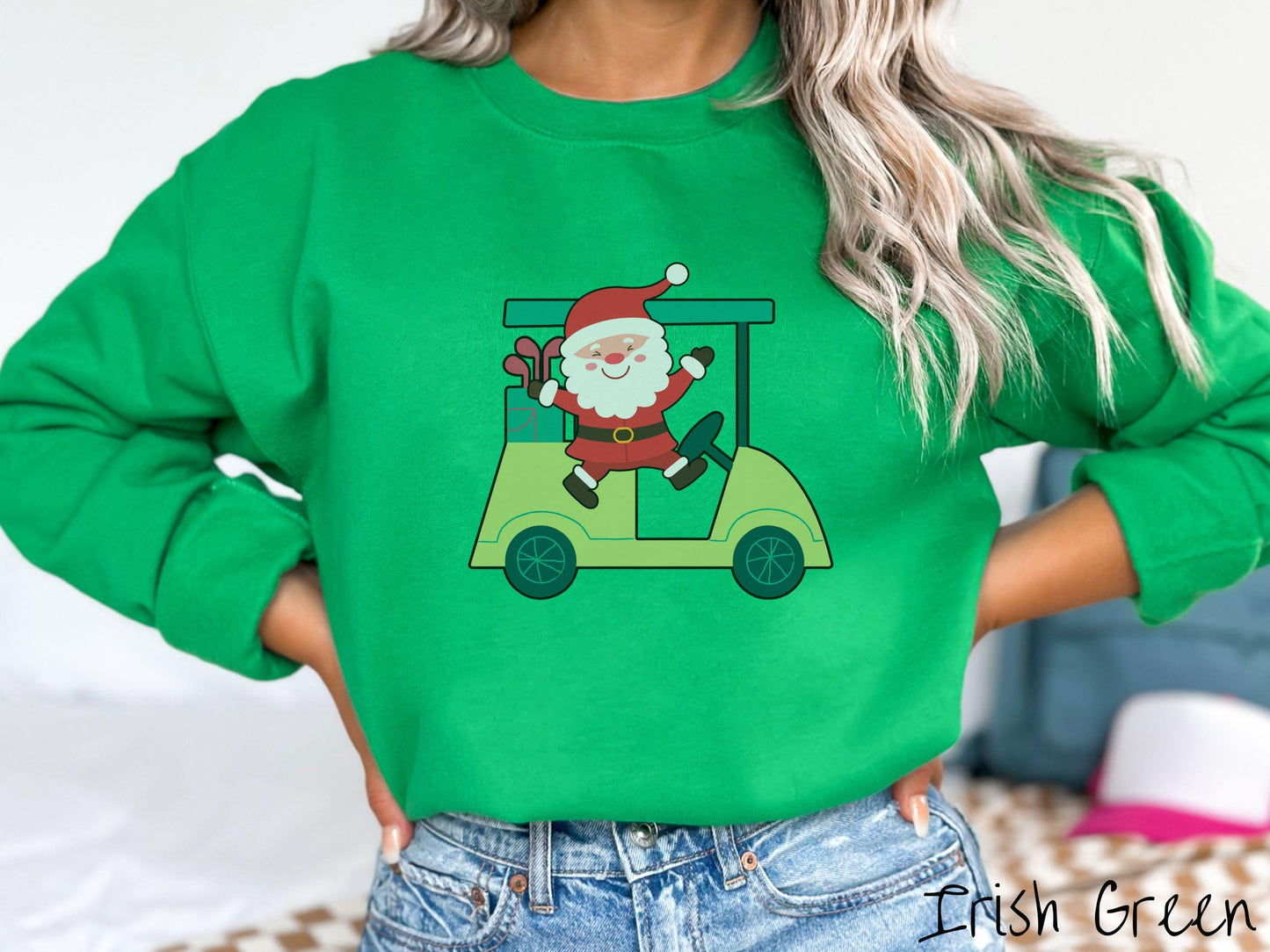 A woman wearing a cute irish green colored sweatshirt with smiling Santa driving a green golf cart and waving with both hands.