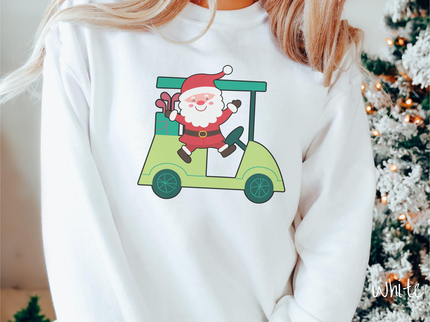 A woman wearing a cute white colored sweatshirt with smiling Santa driving a green golf cart and waving with both hands.