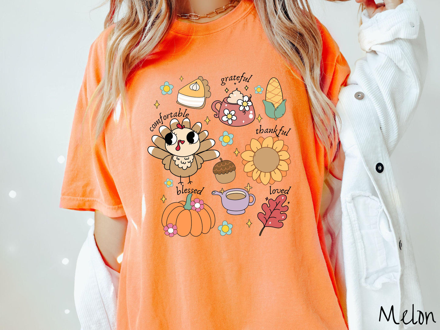 A woman wearing a cute, vintage melon colored Comfort Colors T-shirt with text grateful comfortable thankful blessed and love. In a grid format are a piece of pumpkin pie, a coffee mug, corn, a turkey, a sunflower, a pumpkin, a leaf, and an acorn.