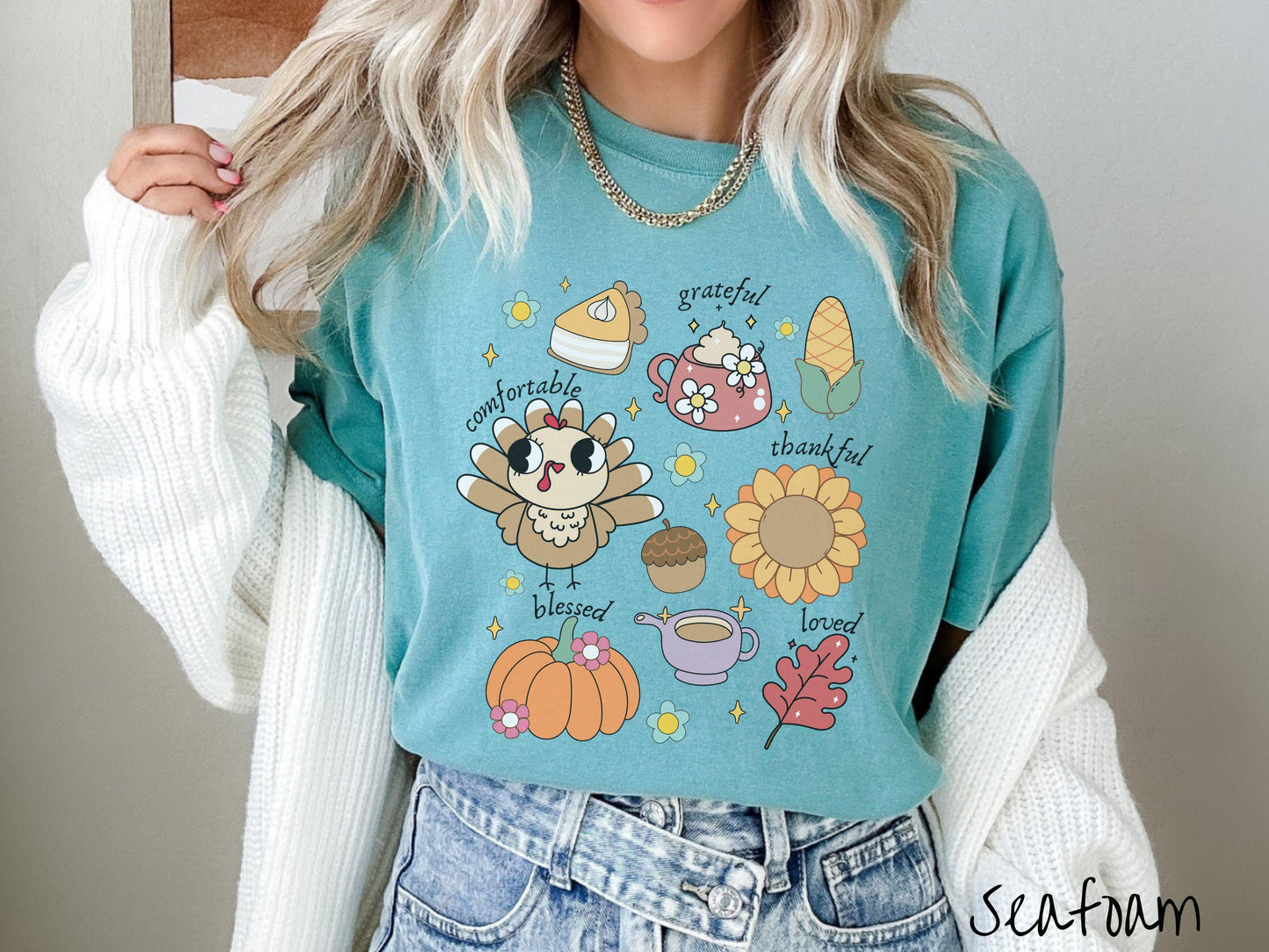 A woman wearing a cute, vintage seafoam colored Comfort Colors T-shirt with text grateful comfortable thankful blessed and love. In a grid format are a piece of pumpkin pie, a coffee mug, corn, a turkey, a sunflower, a pumpkin, a leaf, and an acorn.
