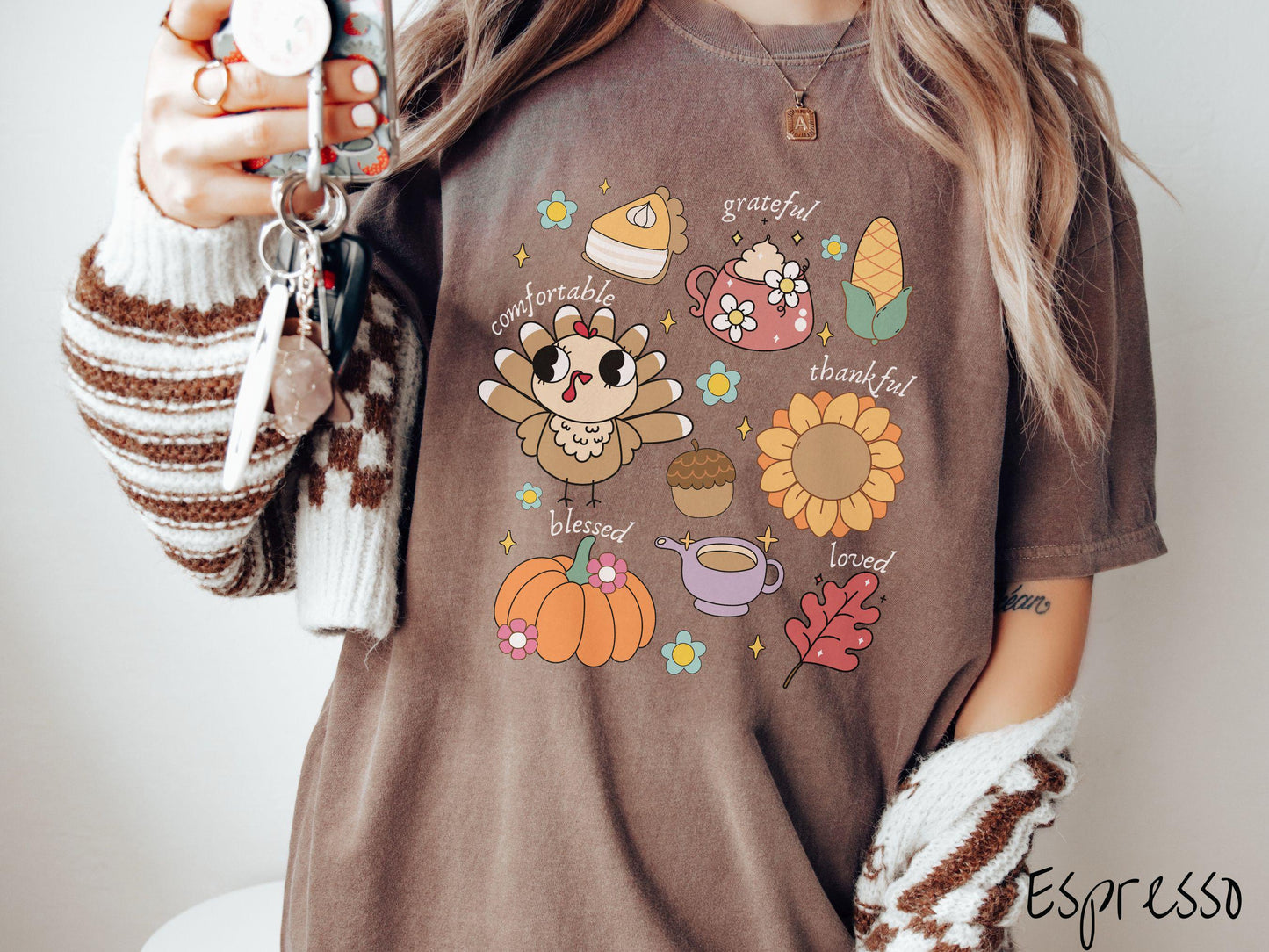 A woman wearing a cute, vintage espresso colored Comfort Colors T-shirt with text grateful comfortable thankful blessed and love. In a grid format are a piece of pumpkin pie, a coffee mug, corn, a turkey, a sunflower, a pumpkin, a leaf, and an acorn.
