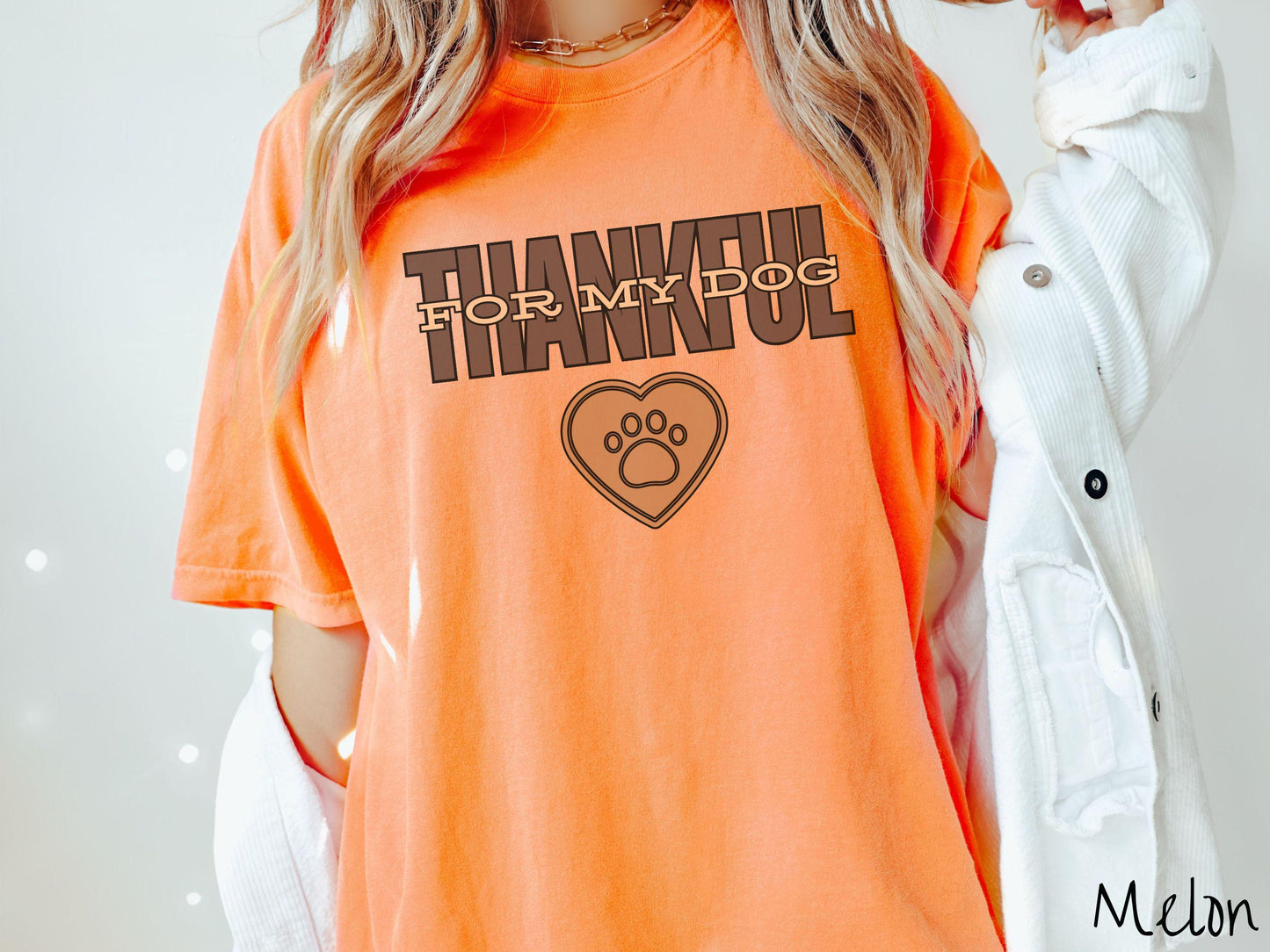 A woman wearing a cute, vintage melon colored Comfort Colors T-shirt with the text Thankful for My Dog across the top in two shades of brown. Below is a brown heart with a dog paw print in the middle.