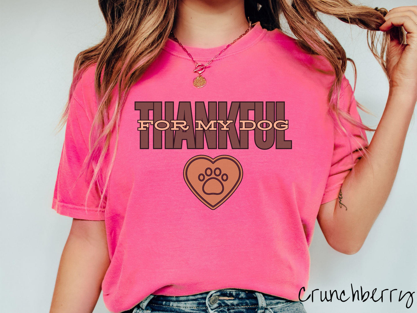 A woman wearing a cute, vintage crunchbery colored Comfort Colors T-shirt with the text Thankful for My Dog across the top in two shades of brown. Below is a brown heart with a dog paw print in the middle.