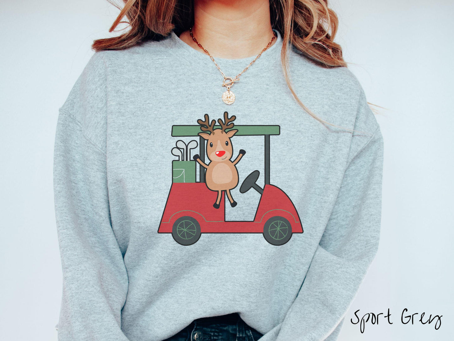 A woman wearing a cute sport grey colored sweatshirt with smiling reindeer driving a red golf cart and waving with both hands.