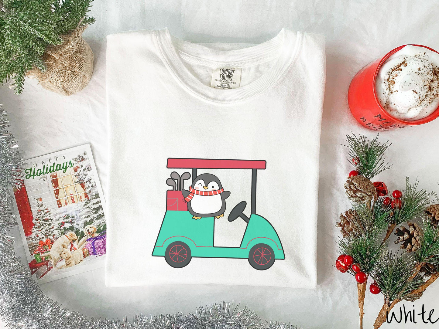 A woman wearing a cute white colored shirt with smiling penguin driving a green golf cart and waving with both hands.