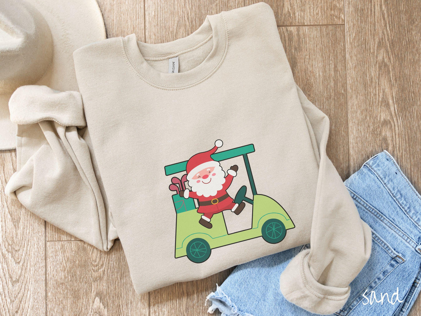 A woman wearing a cute sand colored sweatshirt with smiling Santa driving a green golf cart and waving with both hands.