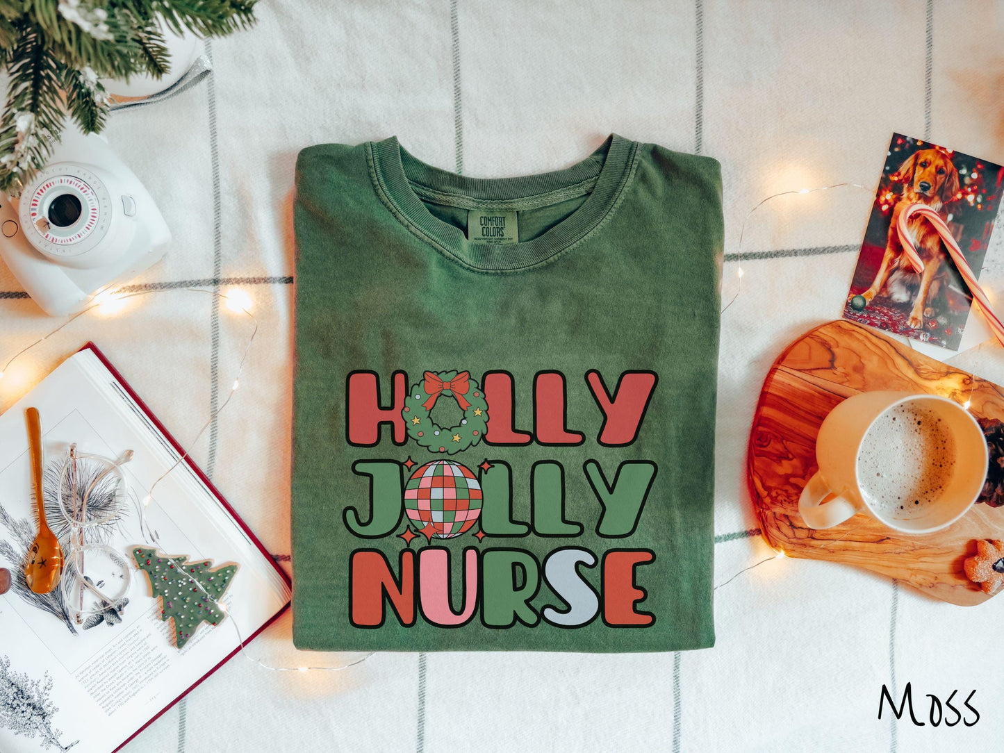 A cute, vintage moss colored Comfort Colors T-shirt with text Holly Jolly Nurse in red, green , pink, and cadet blue font. The letter O in Holly is a Christmas wreath and the letter O in Jolly is a red, green, and blue disco ball.