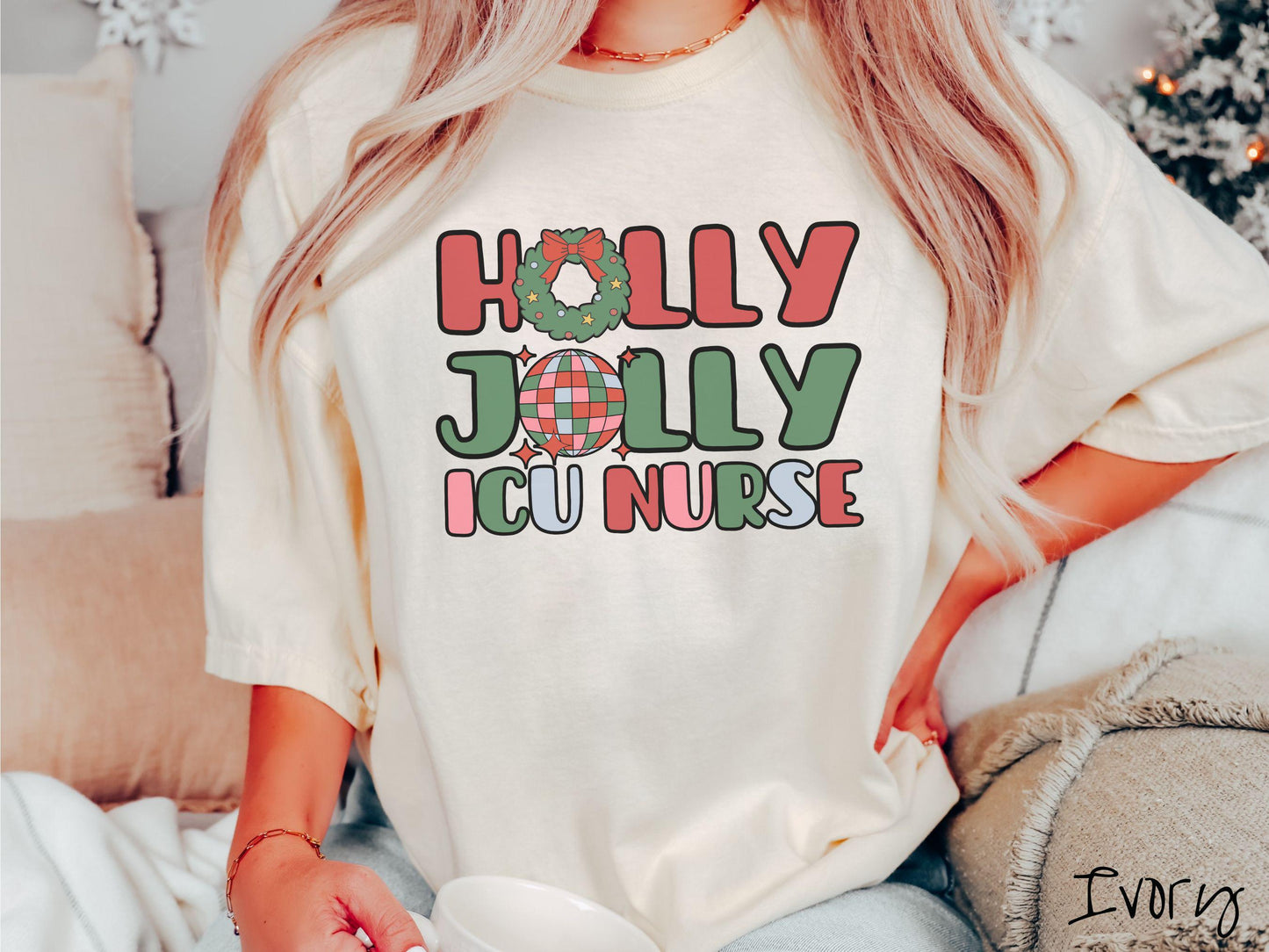 A woman wearing a cute, vintage ivory colored Comfort Colors T-shirt with the text Holly Jolly ICU Nurse in red, green, pink, and blue font. The letter O in Holly is a Christmas wreath and the letter O in Jolly is a multi-colored disco ball.