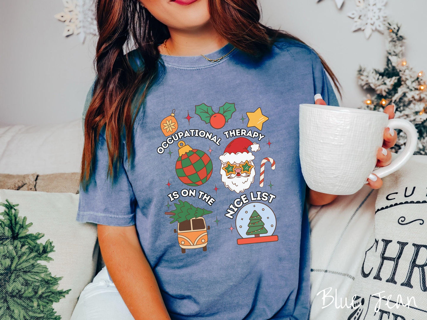This vintage blue jean colored Comfort Colors T-shirt features the text 'Occupational Therapy is on the nice list' in white font, surrounded by Christmas lights, cranberries, Santa Claus, a candy cane, a snow globe, and other festive decorations.