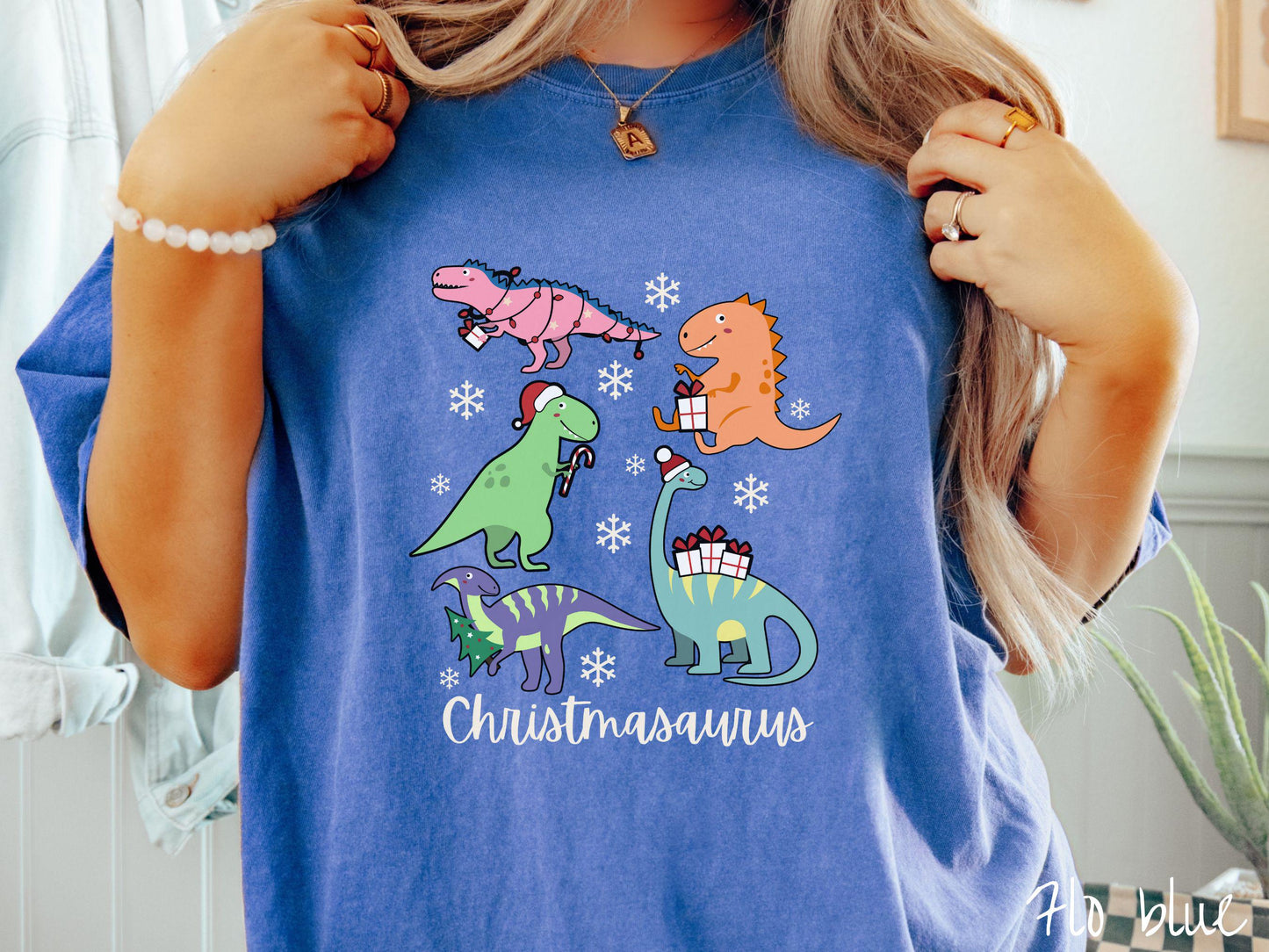 Get into the festive spirit with this adorable flo blue colored Christmasaurus Comfort Colors T-shirt. Featuring a variety of colorful dinosaurs dressed up for the holidays, this tee exudes a playful and cheerful vibe.