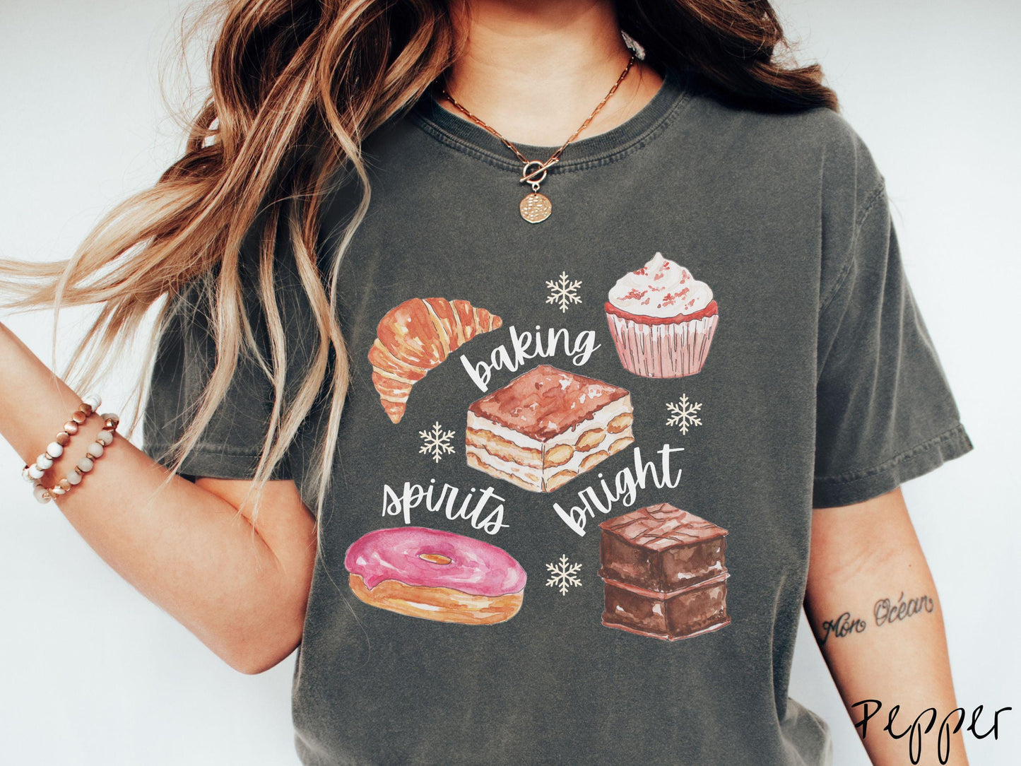 This vintage pepper colored Comfort Colors T-shirt features the text 'baking spirits bright' in white cursive font, accompanied by cute dessert illustrations and white snowflakes.