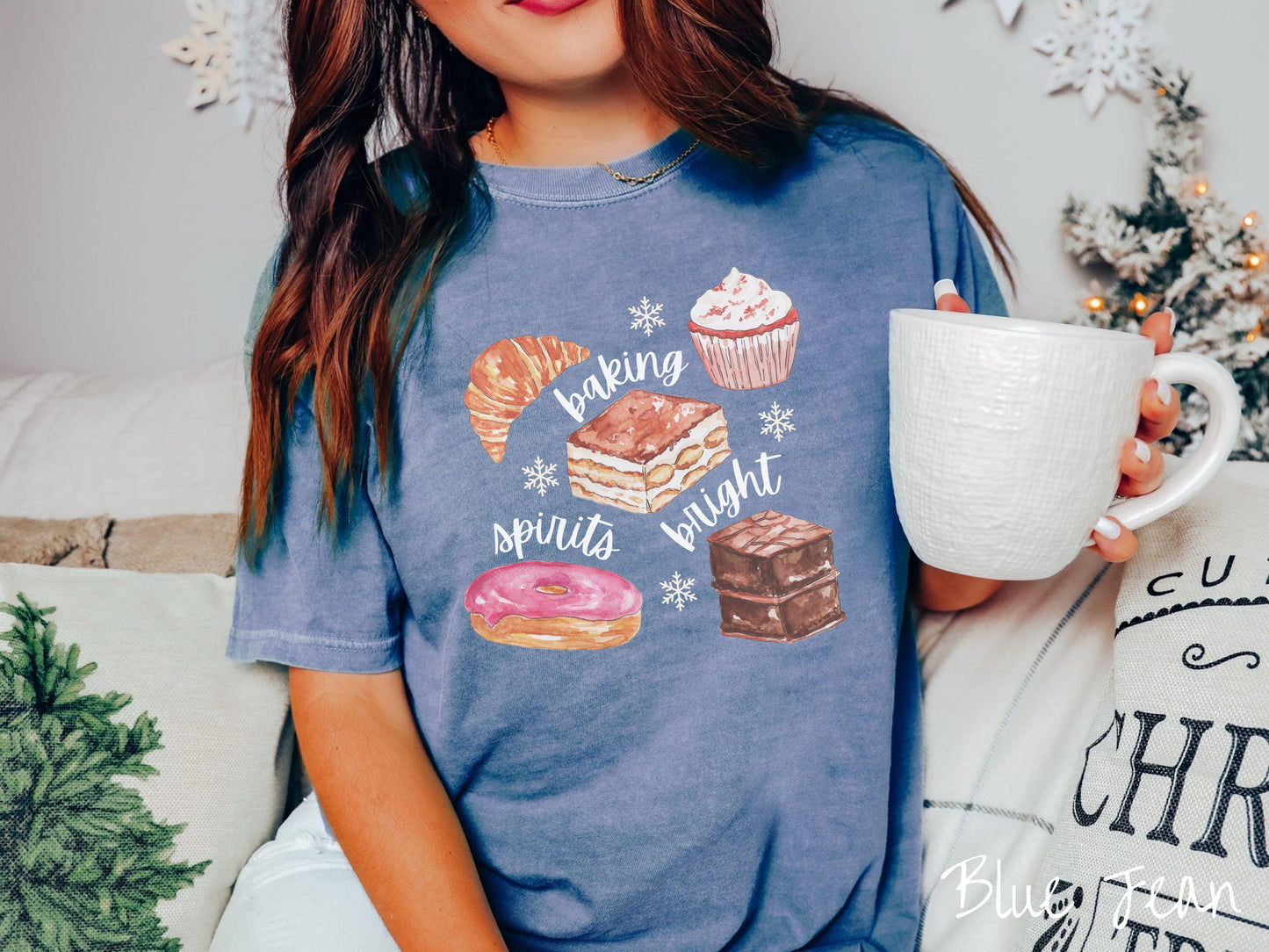 This vintage blue jean colored Comfort Colors T-shirt features the text 'baking spirits bright' in white cursive font, accompanied by cute dessert illustrations and white snowflakes.