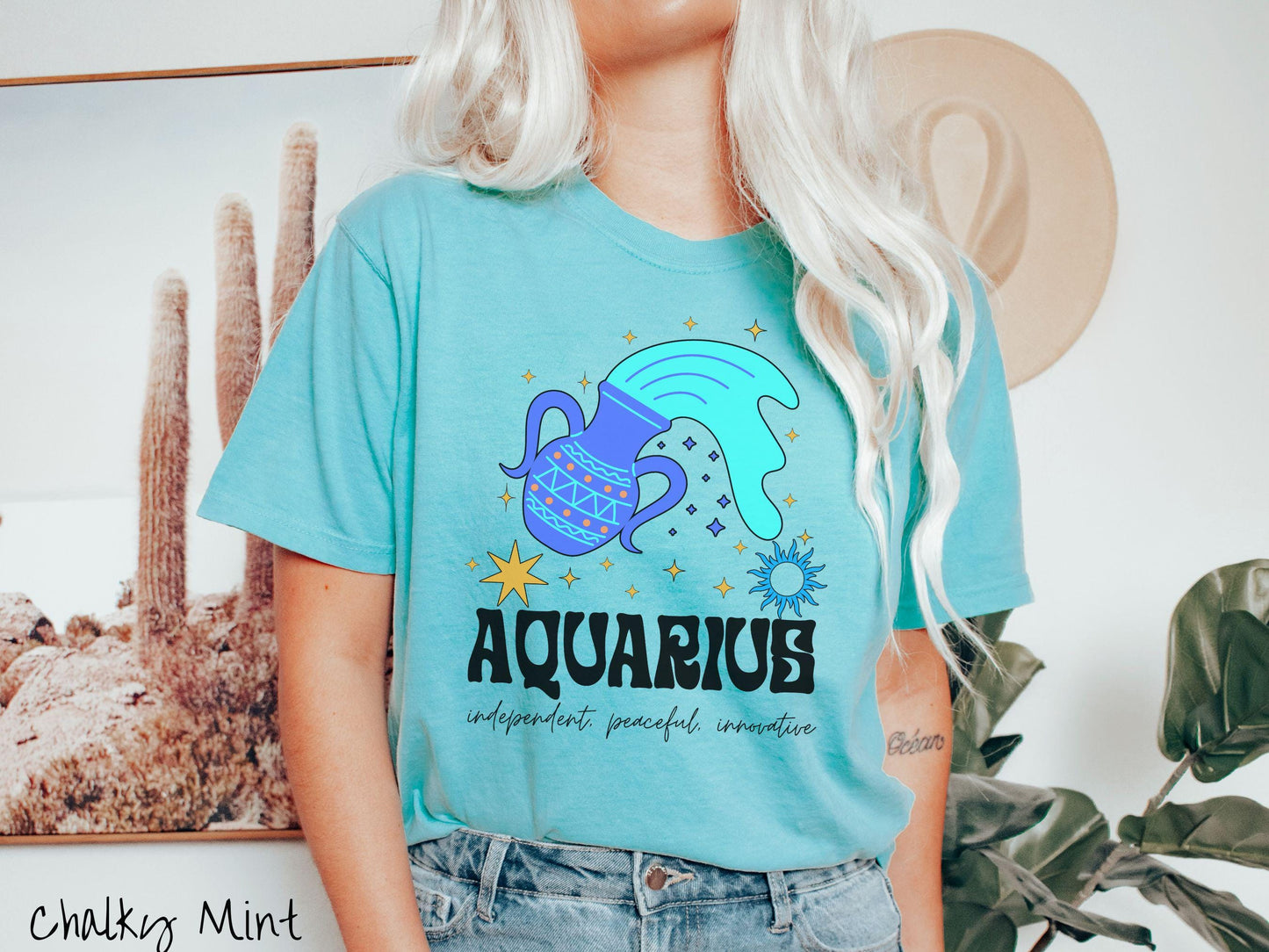 A vintage chalky mint colored Comfort Colors T-shirt features a large purple urn surrounded by stars, with the text Aquarius and the words independent, peaceful, innovative.