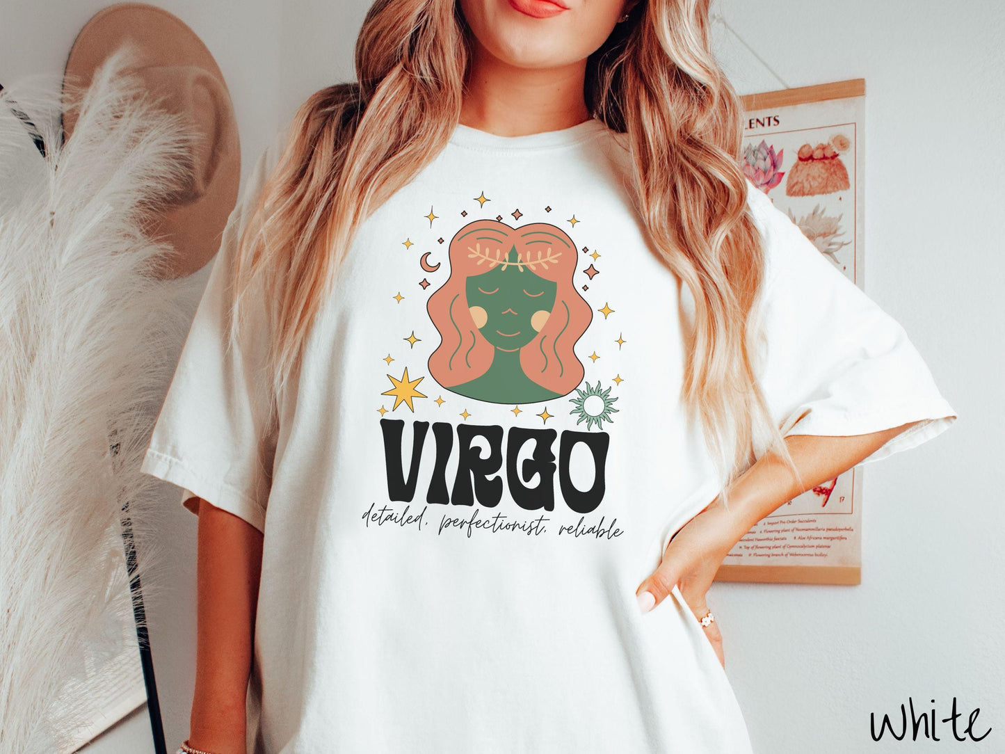 A vintage white colored Comfort Colors T-shirt features a green and brown woman wearing a wheat tiara surrounded by stars and the sun with text Virgo in large bold font and below that are the words detailed, perfectionist, reliable in cursive font.