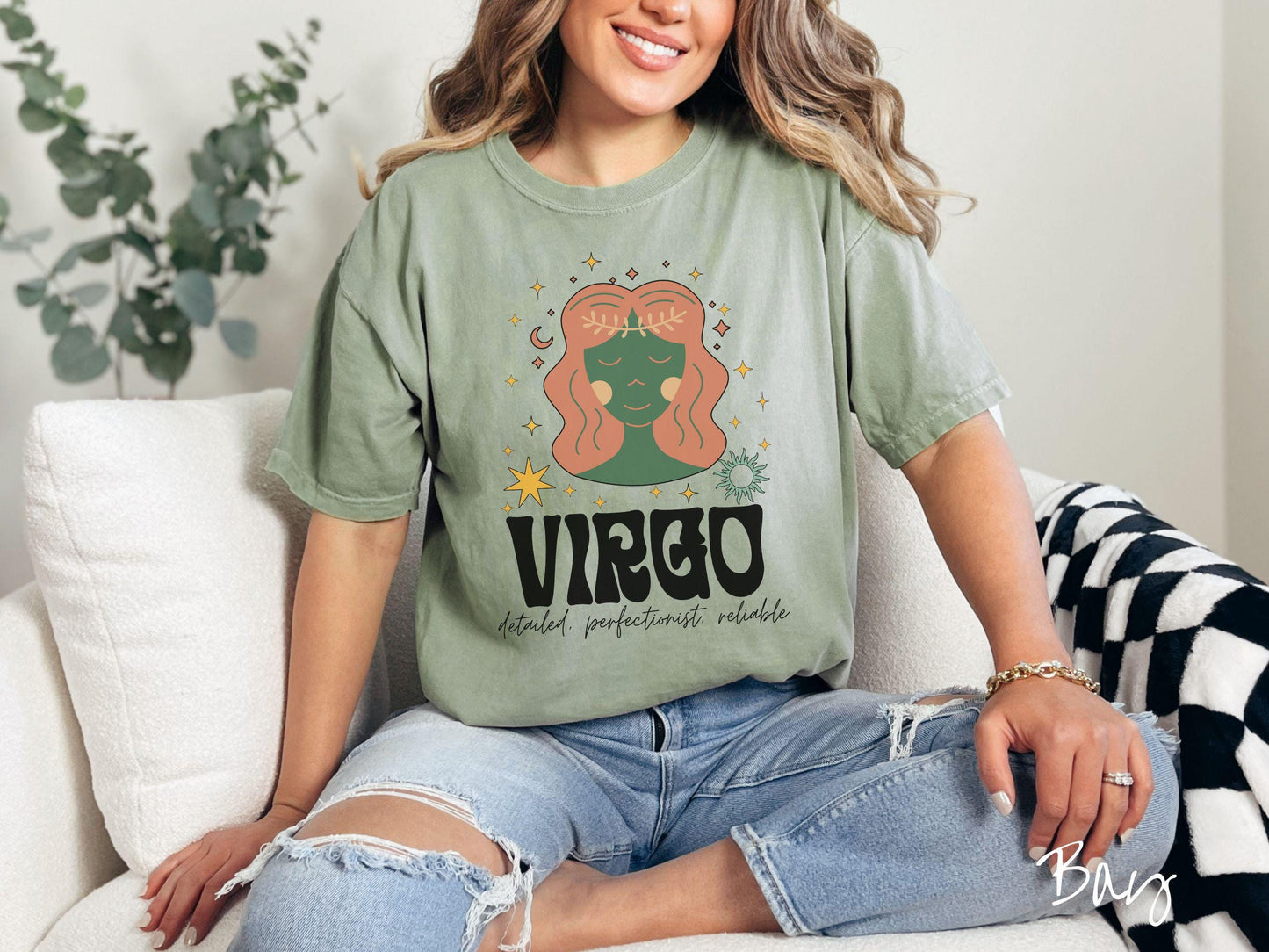 A vintage bay colored Comfort Colors T-shirt features a green and brown woman wearing a wheat tiara surrounded by stars and the sun with text Virgo in large bold font and below that are the words detailed, perfectionist, reliable in cursive font.