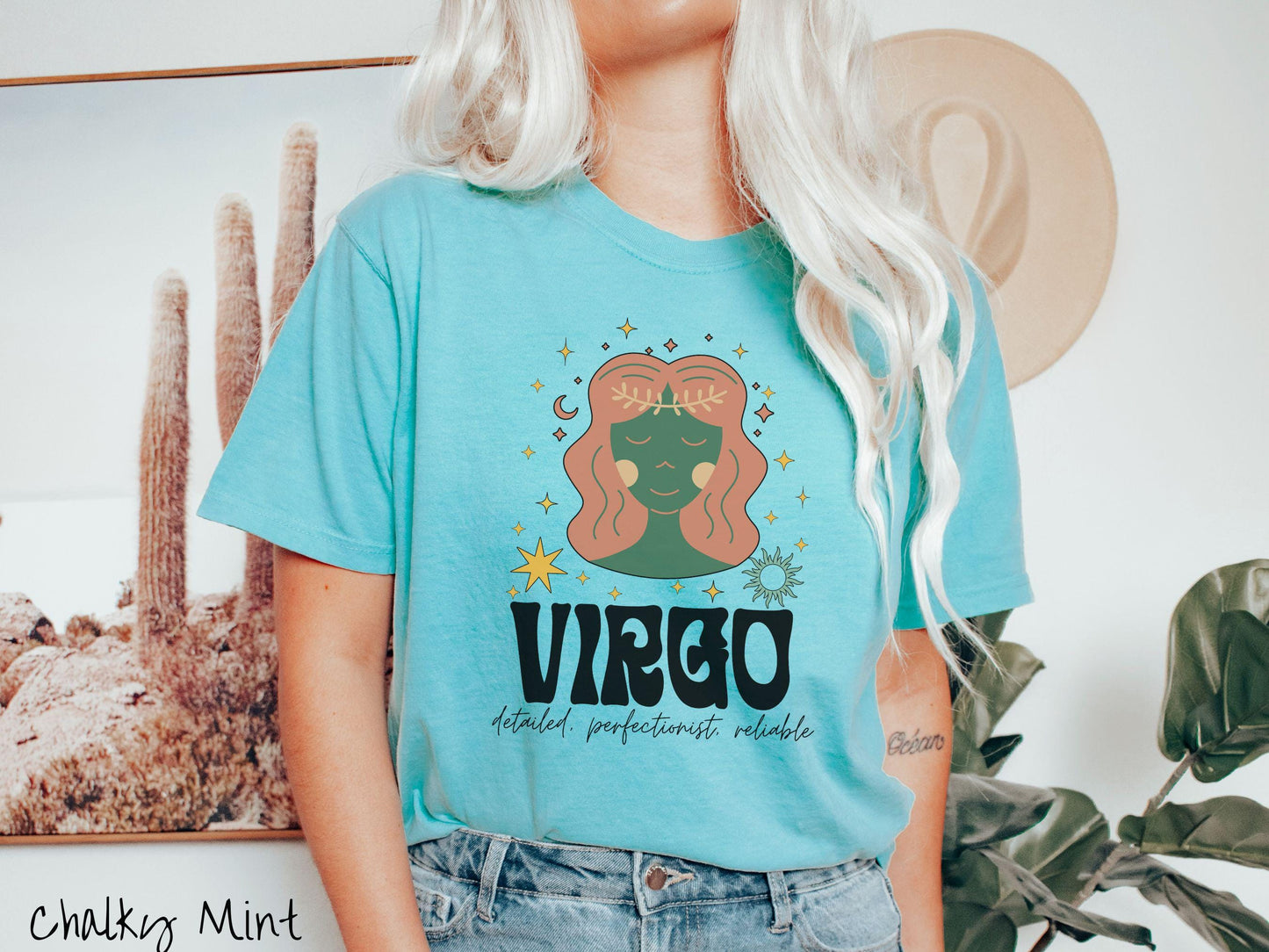 A vintage chalky mint colored Comfort Colors T-shirt features a green and brown woman wearing a wheat tiara surrounded by stars and sun with text Virgo in large bold font and below that are the words detailed, perfectionist, reliable in cursive font.