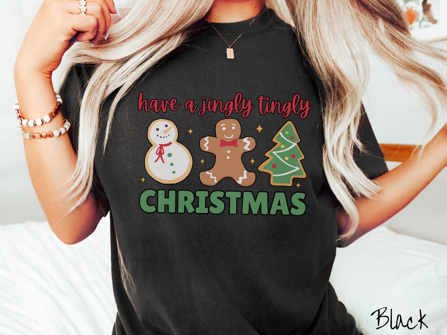 A vintage black colored Christmas Comfort Colors t-shirt featuring a snowman iced cookie, a gingerbread man cookie, and a Christmas tree cookie. The text reads 'have a jingly tingly Christmas' in red and green font.