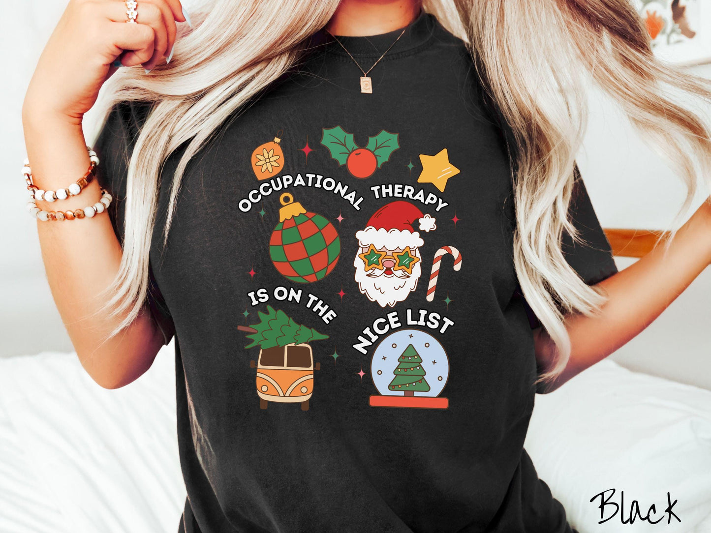 This vintage black colored Comfort Colors T-shirt features the text 'Occupational Therapy is on the nice list' in white font, surrounded by Christmas lights, cranberries, Santa Claus, a candy cane, a snow globe, and other festive decorations.