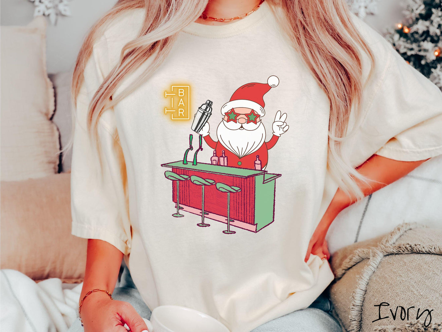 A vintage ivory colored Comfort Colors T-shirt features Santa Claus with red and green glasses mixing drinks and holding up a peace sign behind a red and green bar.