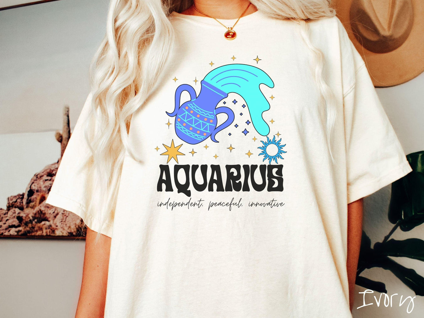 A vintage ivory colored Comfort Colors T-shirt features a large purple urn surrounded by stars, with the text Aquarius and the words independent, peaceful, innovative.