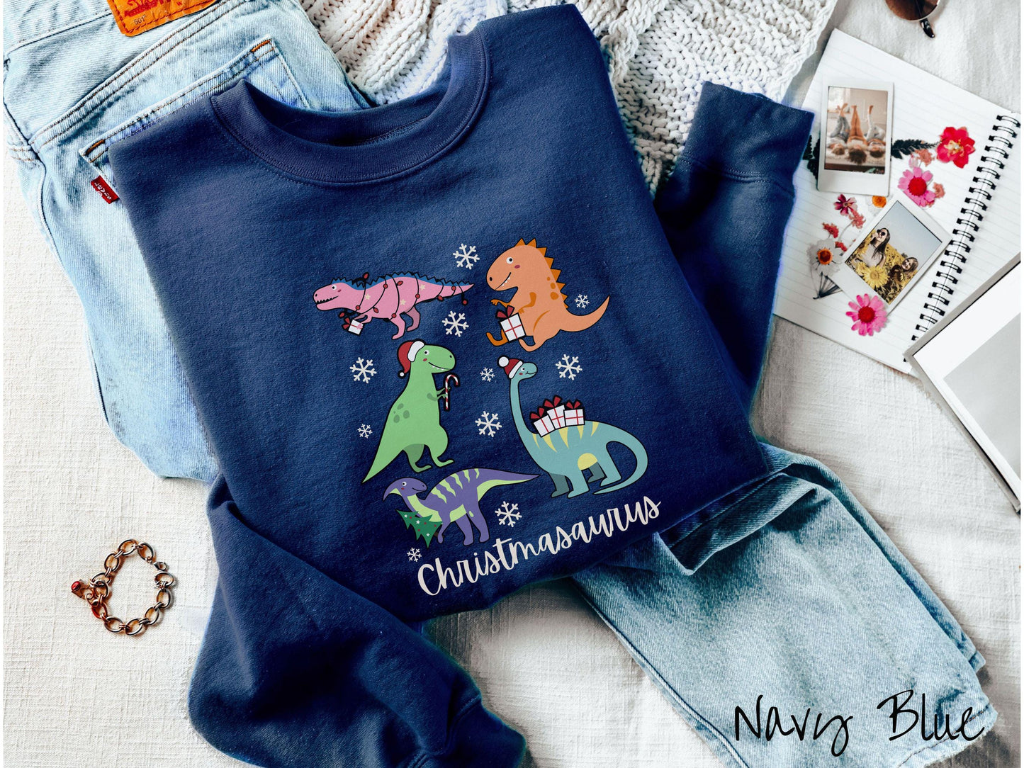 An adorable navy blue colored Christmasaurus Gildan sweatshirt. Featuring a variety of colorful dinosaurs dressed up for the holidays, this sweater exudes a playful and cheerful vibe.