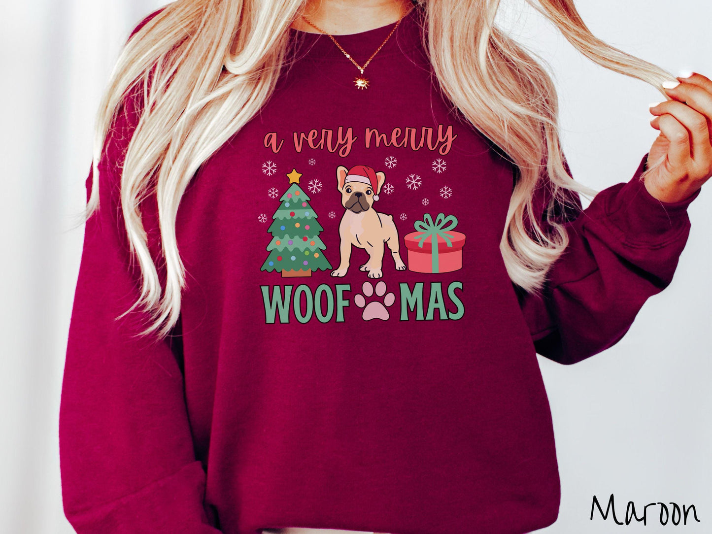 A vintage maroon colored Gildan sweatshirt with text 'a very merry Woofmas' in red and green font, featuring a French Bulldog wearing a red Santa hat sitting between a decorated Christmas tree and a present with white snowflakes hanging in the air.