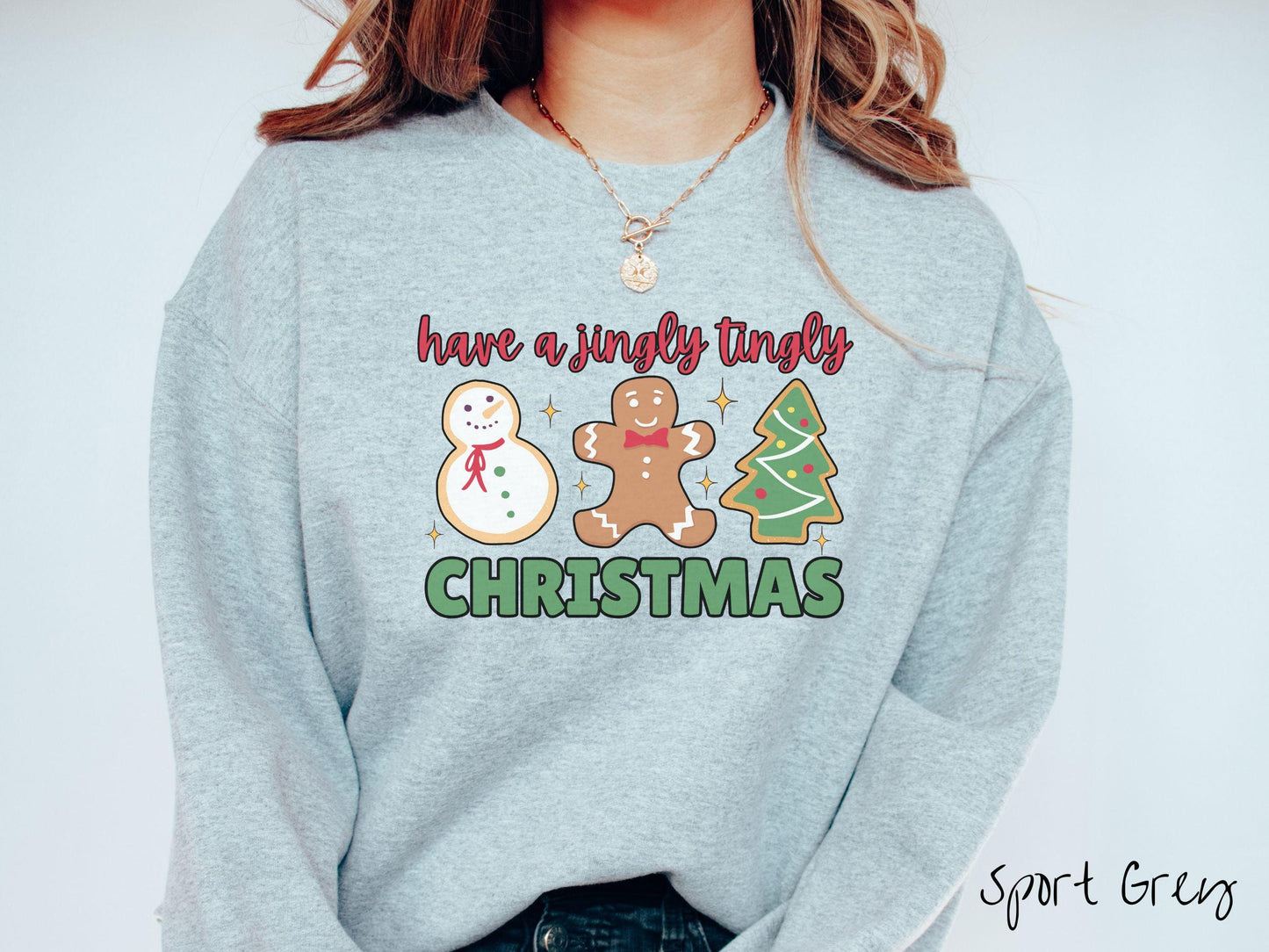 A vintage sport grey colored Christmas Gildan sweatshirt featuring a snowman iced cookie, a gingerbread man cookie, and a Christmas tree cookie. The text reads 'have a jingly tingly Christmas' in red and green font.