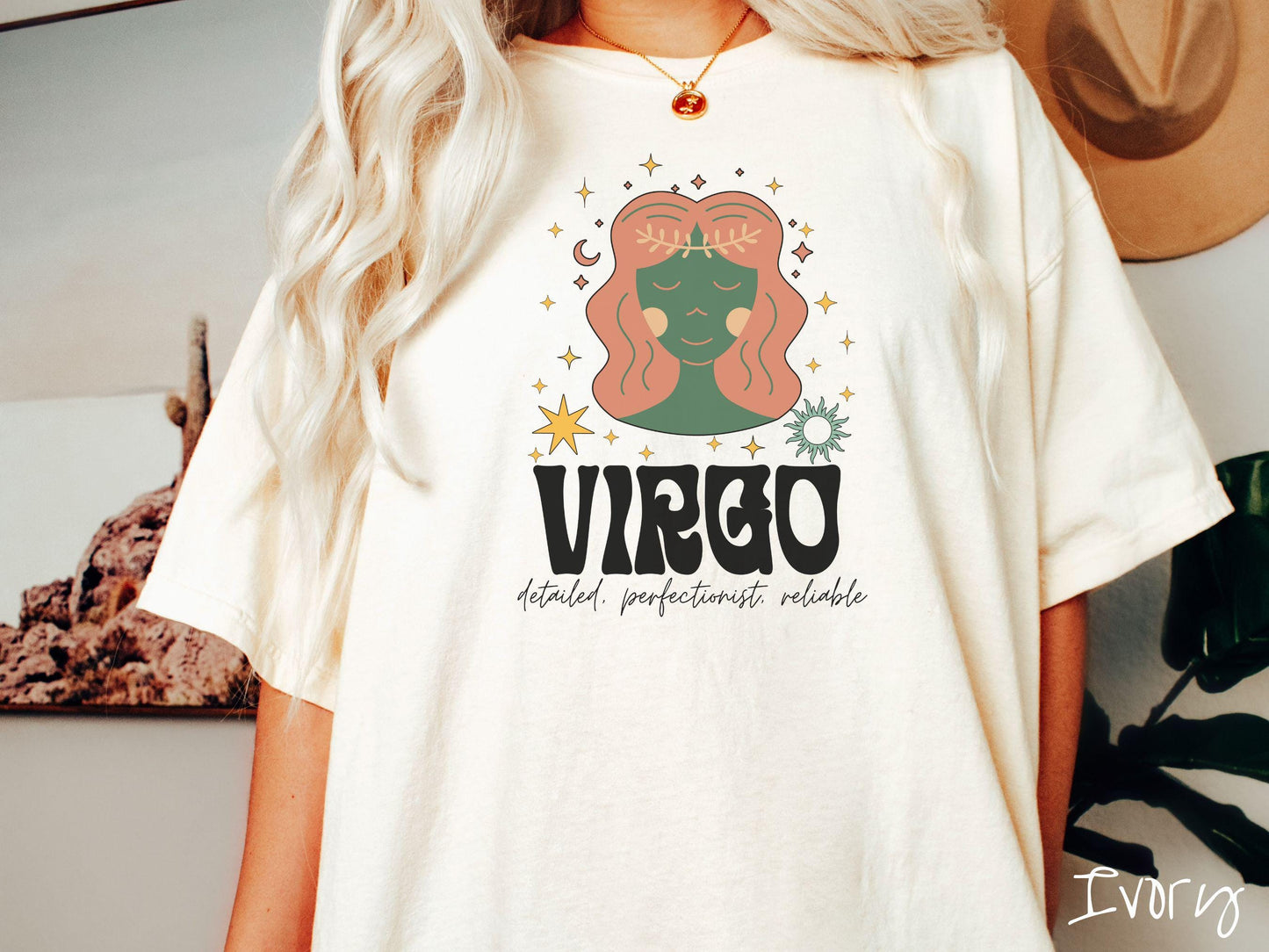 A vintage ivory colored Comfort Colors T-shirt features a green and brown woman wearing a wheat tiara surrounded by stars and the sun with text Virgo in large bold font and below that are the words detailed, perfectionist, reliable in cursive font.
