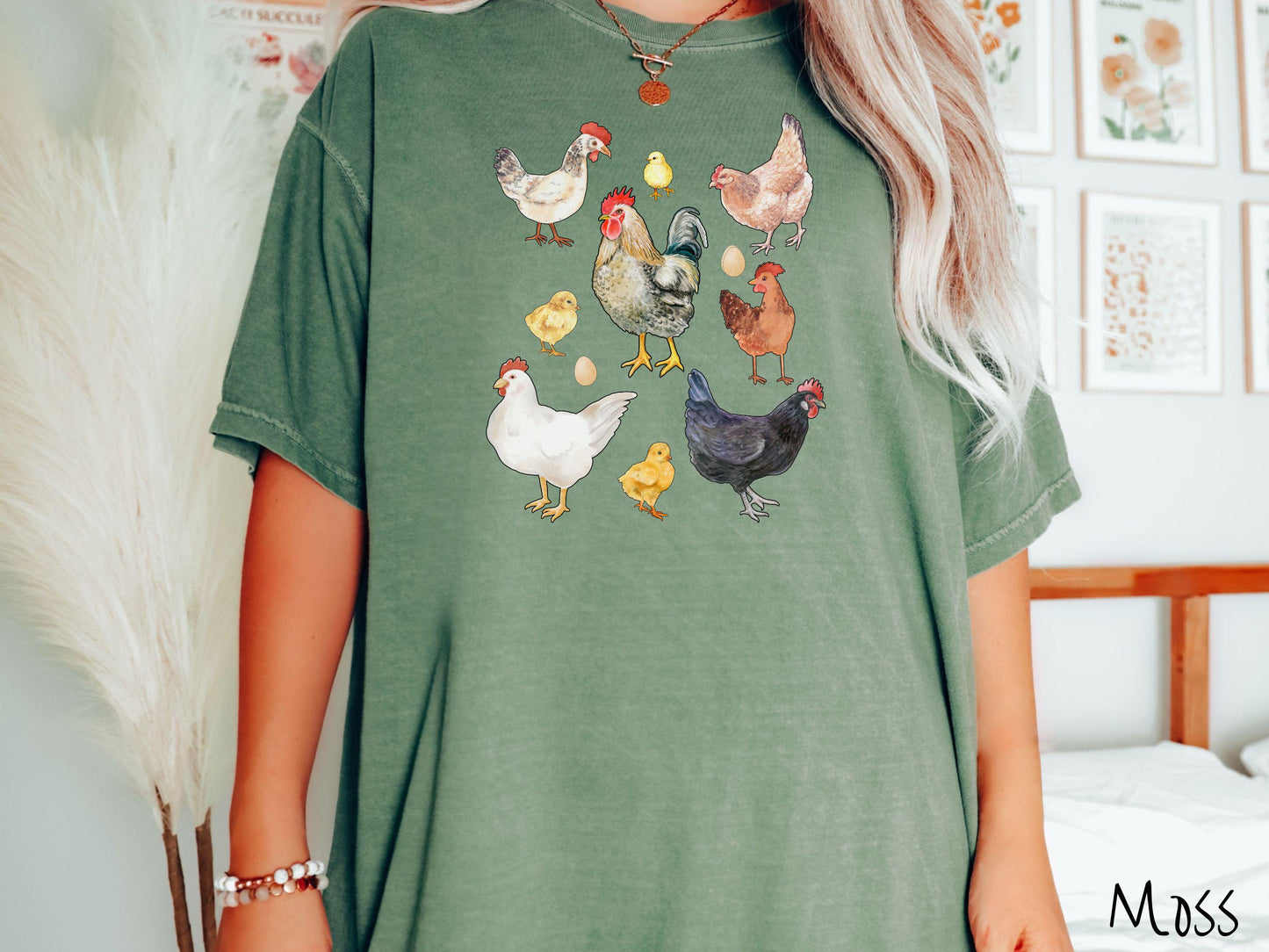 A vintage moss colored Comfort Colors t-shirt featuring a grid style design of assorted colorful chickens, hens, and roosters in a grid design, with chicken eggs scattered among the design.