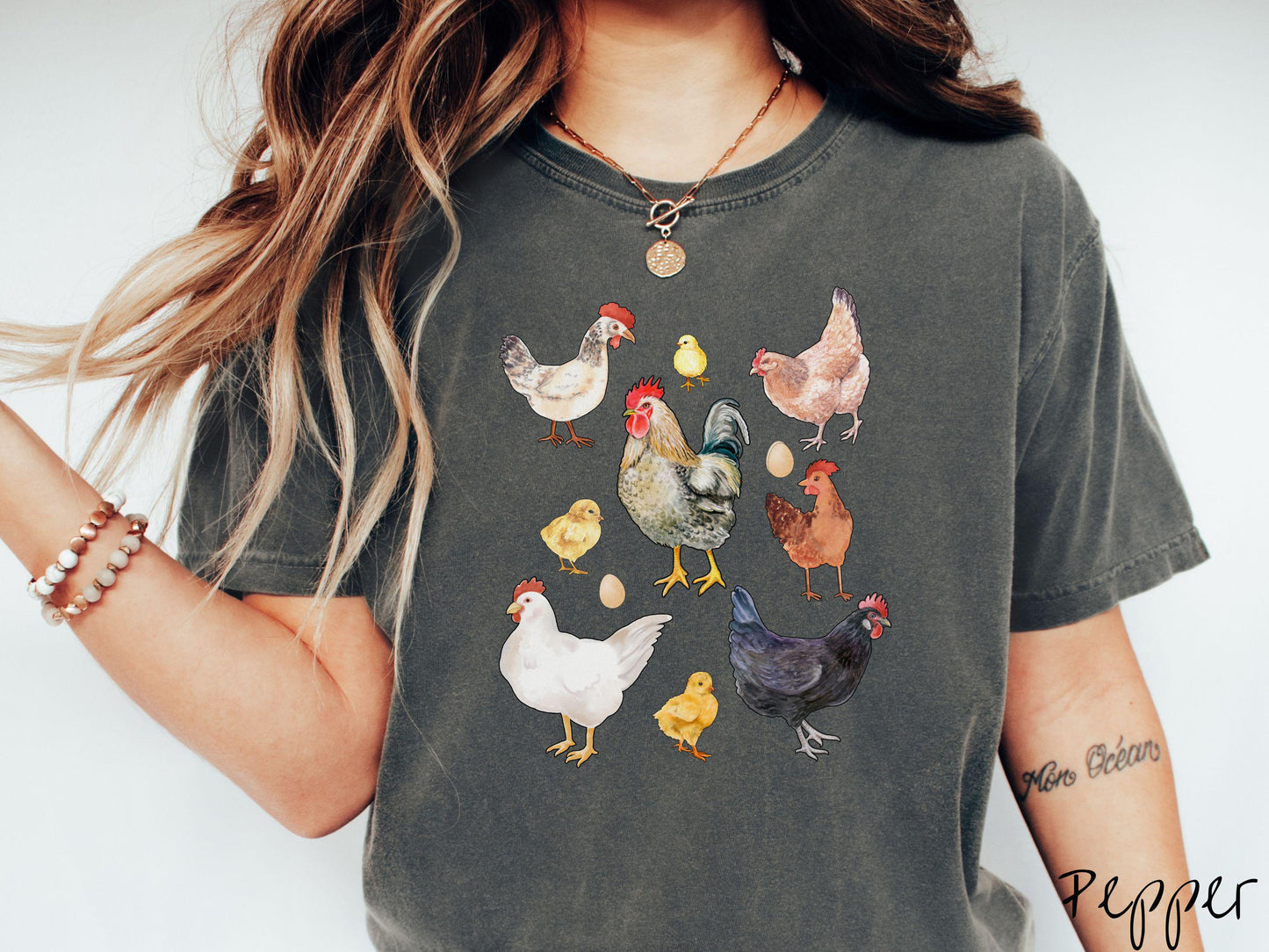A vintage pepper colored Comfort Colors t-shirt featuring a grid style design of assorted colorful chickens, hens, and roosters in a grid design, with chicken eggs scattered among the design.