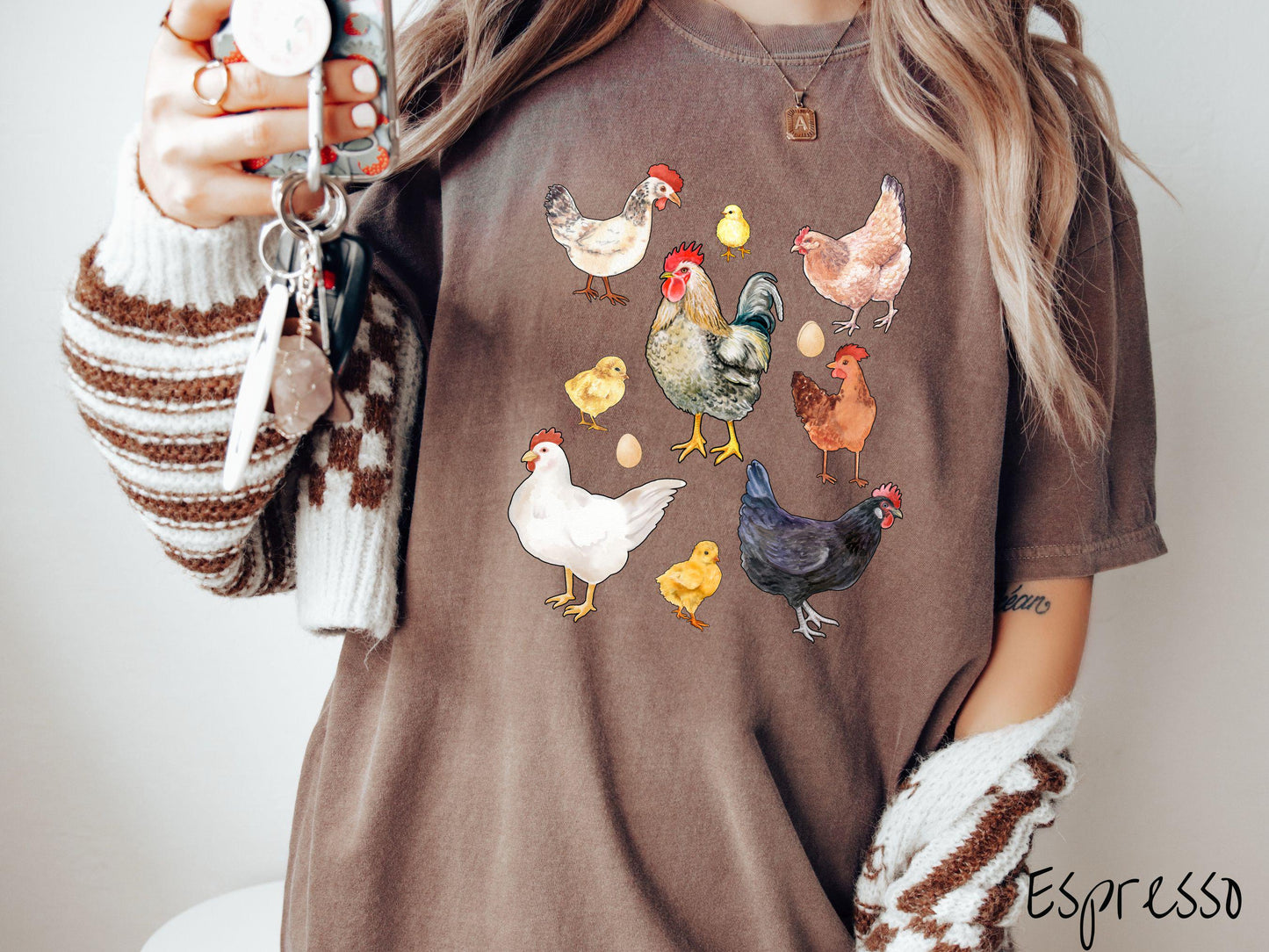 A vintage espresso colored Comfort Colors t-shirt featuring a grid style design of assorted colorful chickens, hens, and roosters in a grid design, with chicken eggs scattered among the design.