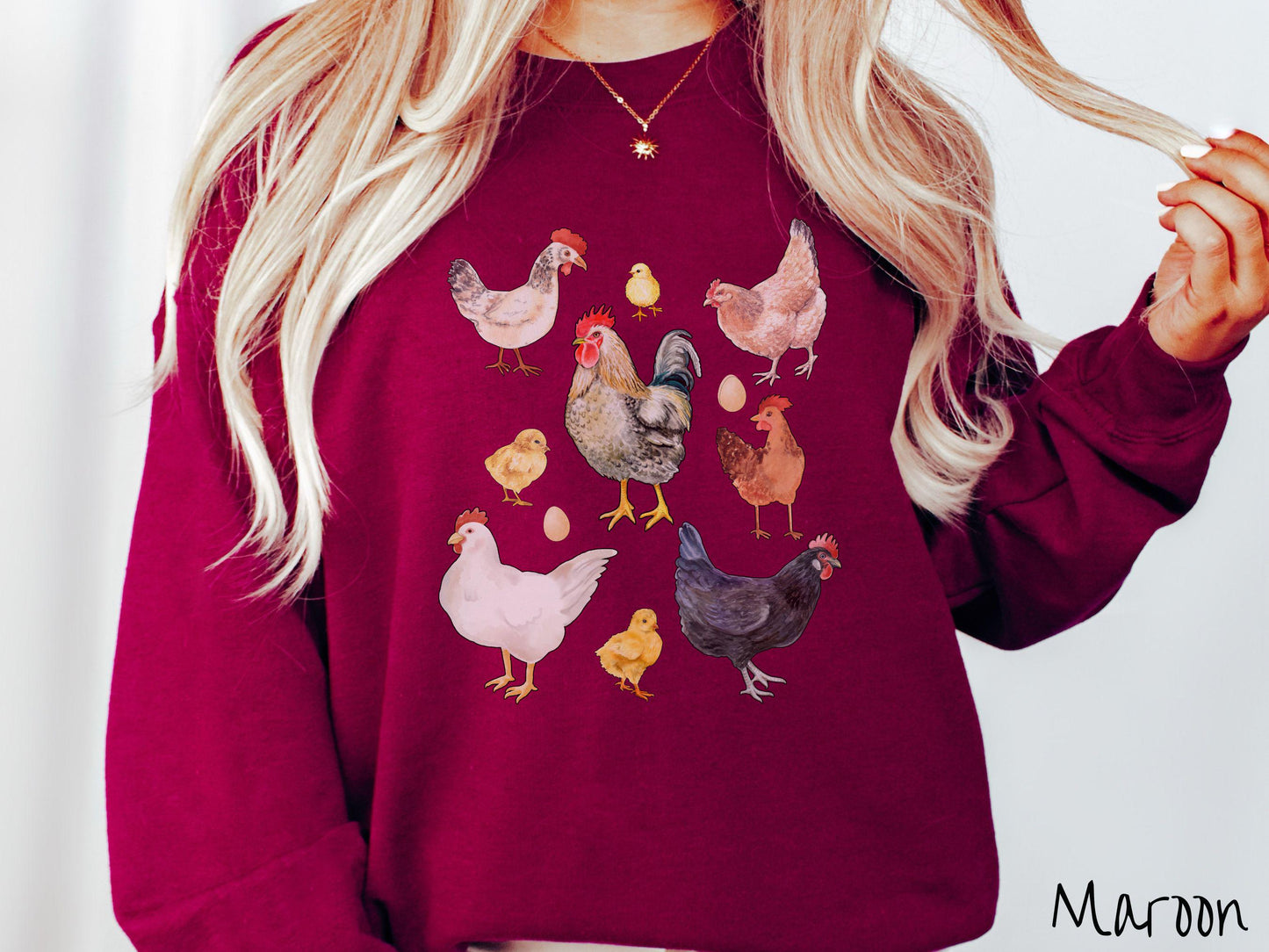 A vintage maroon colored Gildan sweatshirt featuring a grid style design of assorted colorful chickens, hens, and roosters in a grid design, with chicken eggs scattered among the design.
