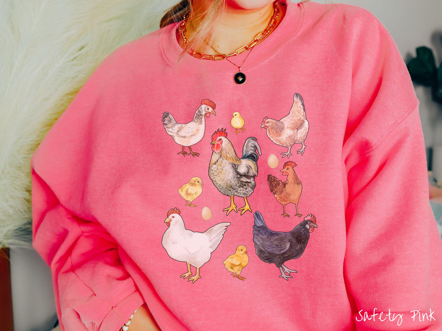 A vintage safety pink colored Gildan sweatshirt featuring a grid style design of assorted colorful chickens, hens, and roosters in a grid design, with chicken eggs scattered among the design.