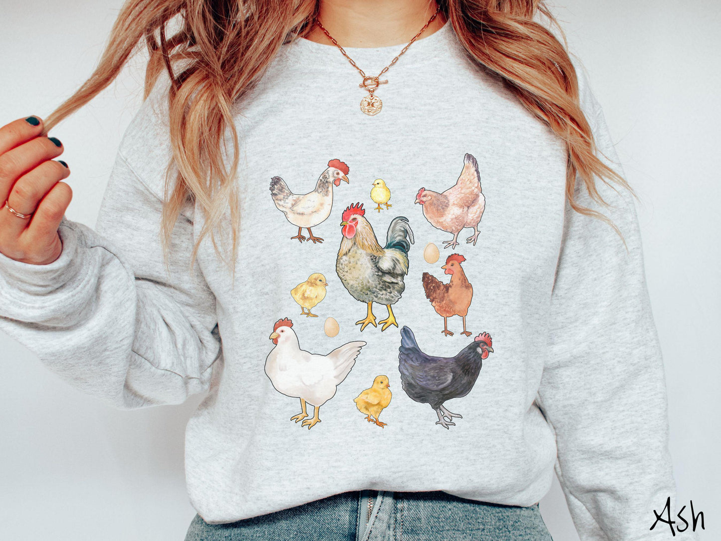 A vintage ash colored Gildan sweatshirt featuring a grid style design of assorted colorful chickens, hens, and roosters in a grid design, with chicken eggs scattered among the design.