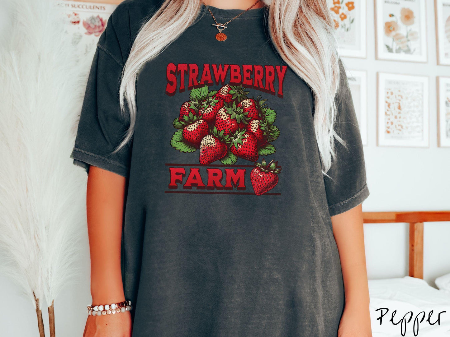 A vintage pepper colored Comfort Colors t-shirt featuring the text Strawberry Farm in red font with a bundle of red strawberries in between the text.