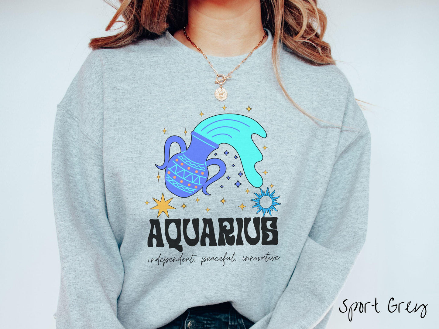 This sport grey colored vintage Comfort Colors sweatshirt features a large purple urn with blue water flowing out of it, surrounded by stars, with the text Aquarius and the words independent, peaceful, innovative.