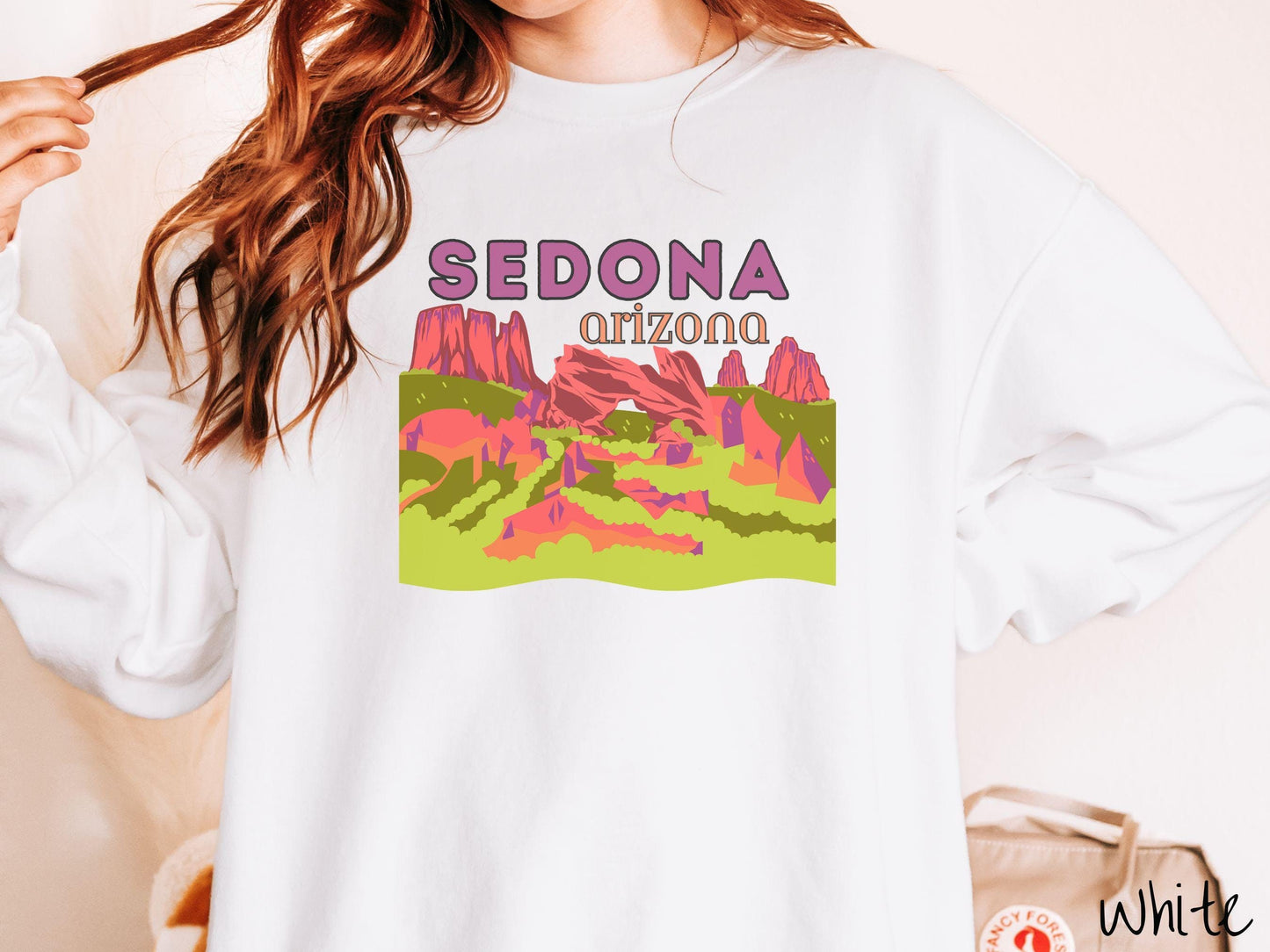 A colorful, vintage white colored Gildan sweatshirt with a scenic viewof Sedona, Arizona. There is an aerial view of the Devil's Bridge rock formation with greenery and rocks in the background.