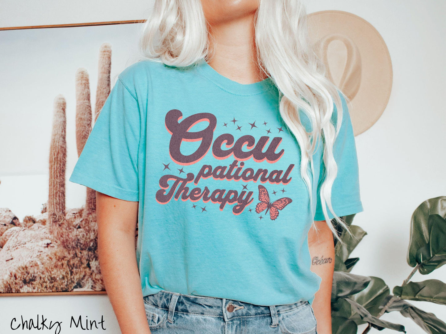 A vintage, chalky mint colored Comfort Colors t-shirt featuring the words Occupational Therapy across the front, this unique design showcases a stunning pink and dark purple butterfly surrounded by delicate twinkling stars.