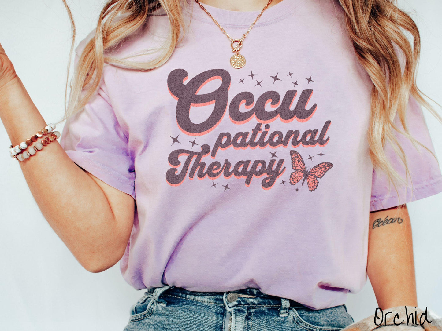 A vintage, orchid colored Comfort Colors t-shirt featuring the words Occupational Therapy across the front, this unique design showcases a stunning pink and dark purple butterfly surrounded by delicate twinkling stars.