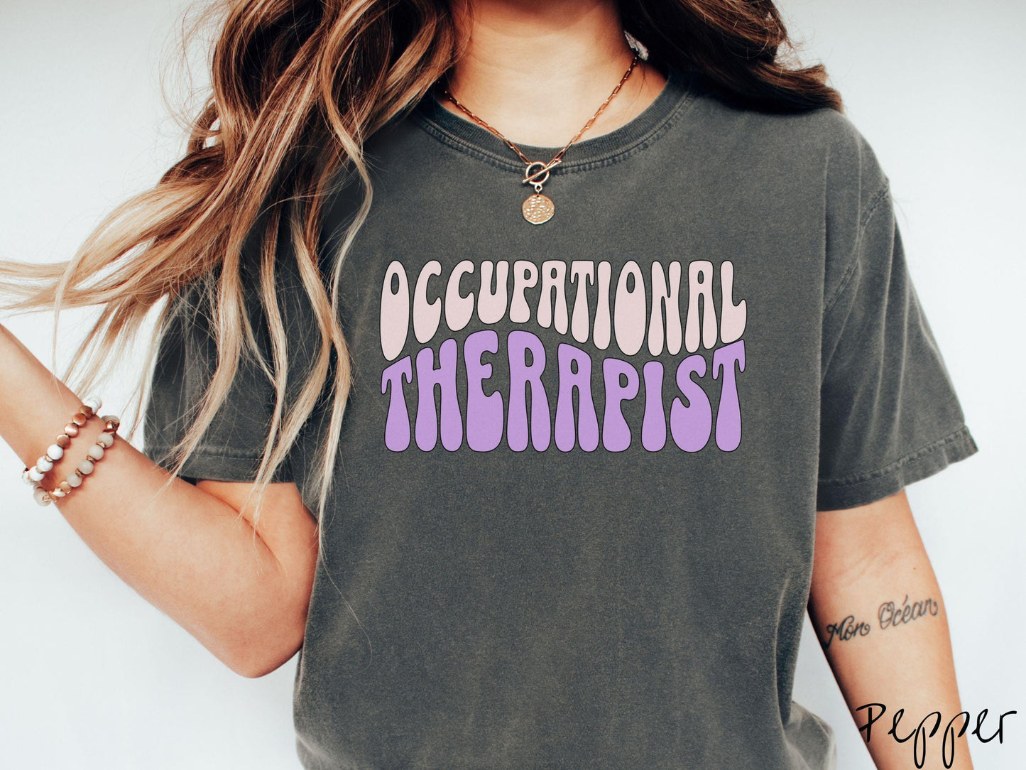 A vintage, pepper colored Comfort Colors t-shirt featuring the text Occupational Therapist in fun wavy font. This sweater is perfect for occupational therapists looking to add a touch of personality to their casual or semi-formal outfits.
