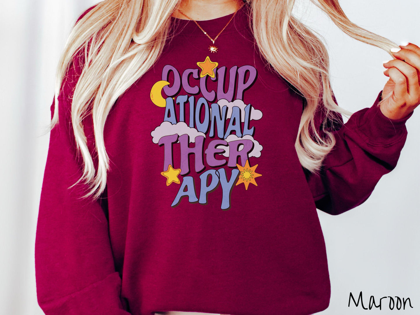 A vintage, maroon colored Gildan sweatshirt with the text Occupational Therapy vertically with clouds, the yellow moon, and bright yellow and orange stars mixed in.