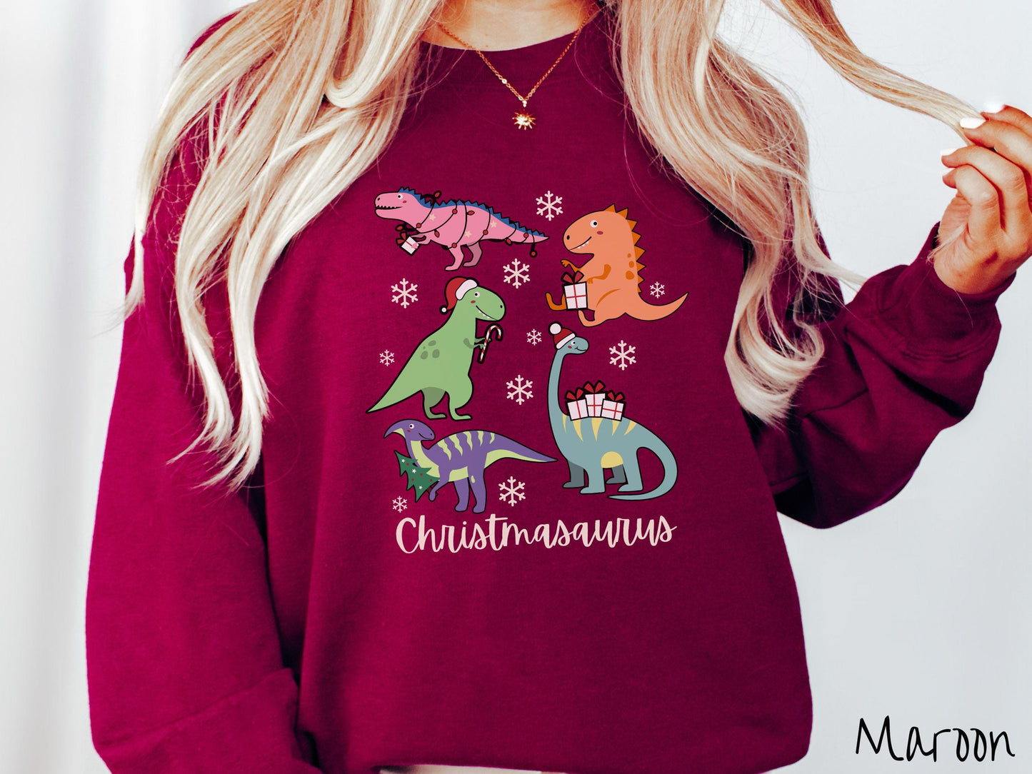 An adorable maroon colored Christmasaurus Gildan sweatshirt. Featuring a variety of colorful dinosaurs dressed up for the holidays, this sweater exudes a playful and cheerful vibe.