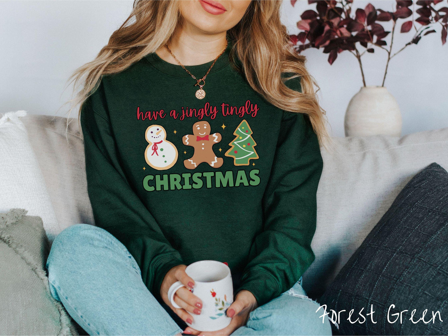 A vintage forest green colored Christmas Gildan sweatshirt featuring a snowman iced cookie, a gingerbread man cookie, and a Christmas tree cookie. The text reads 'have a jingly tingly Christmas' in red and green font.